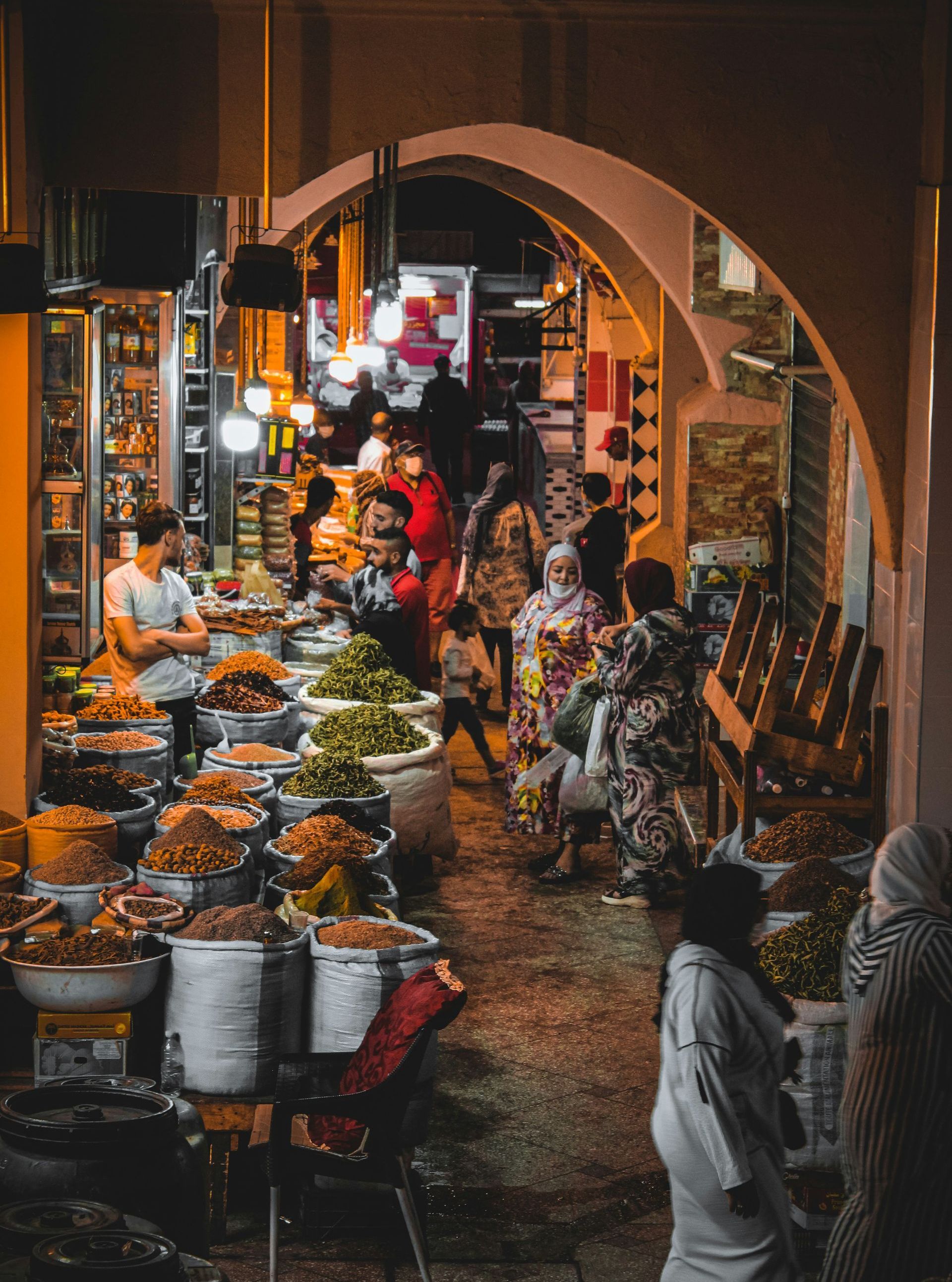 A group of people are standing in a market at night in Morocco.