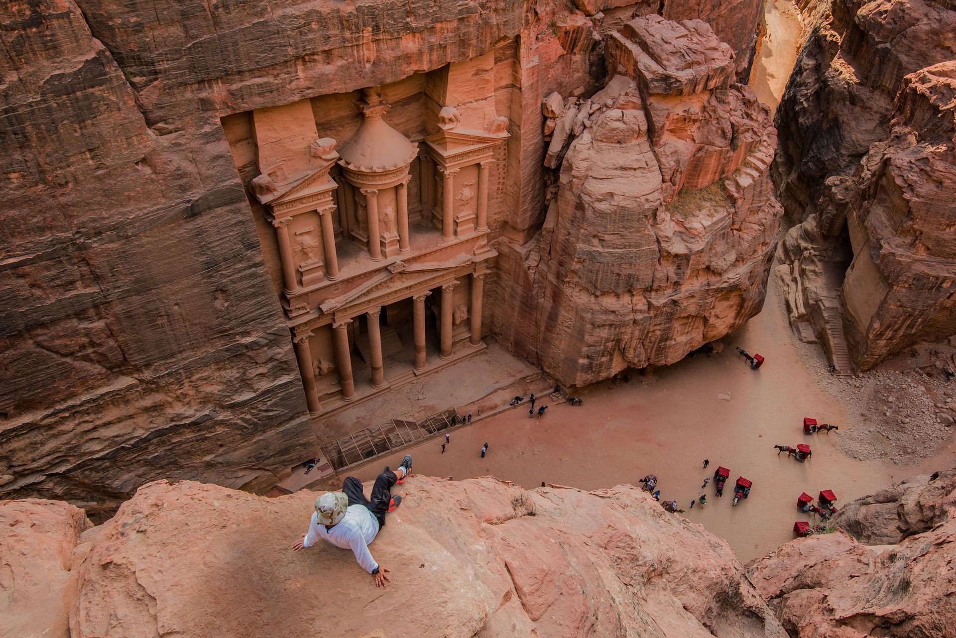 View of Petra's Treasury facade carved into sandstone cliffs; tourists gather below.