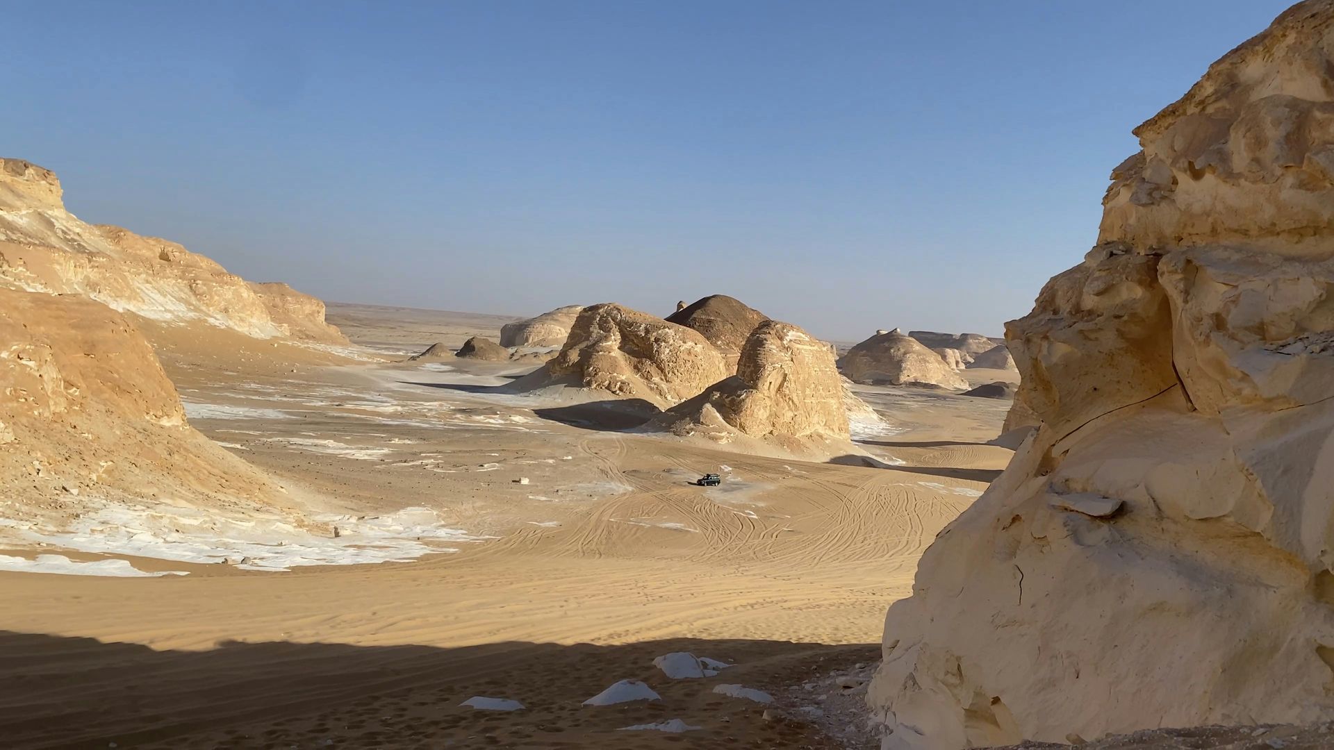White Desert National Park, Egypt with mountains and rocks in the foreground and a blue sky in the background.