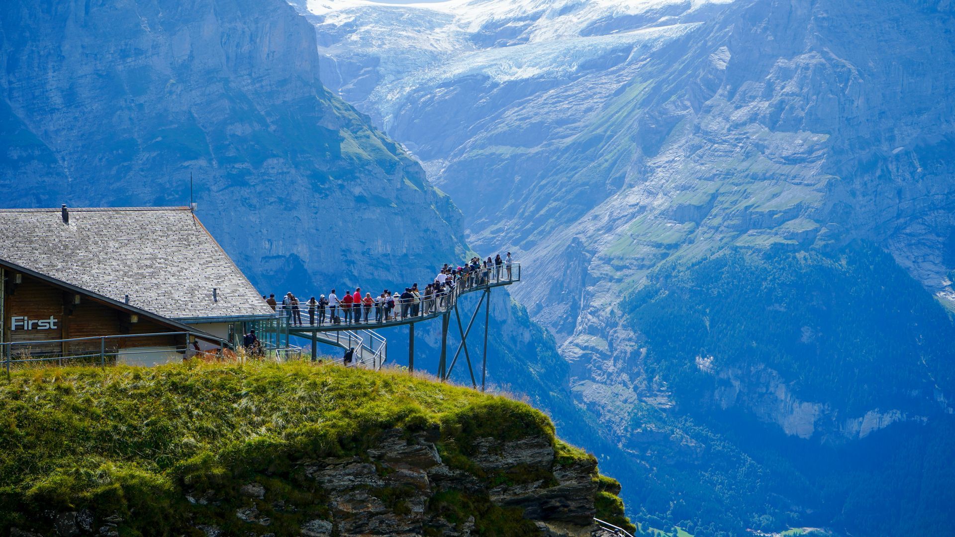 People on a viewing platform, mountain vista, blue sky, and greenery in Interlaken, Switzerland.