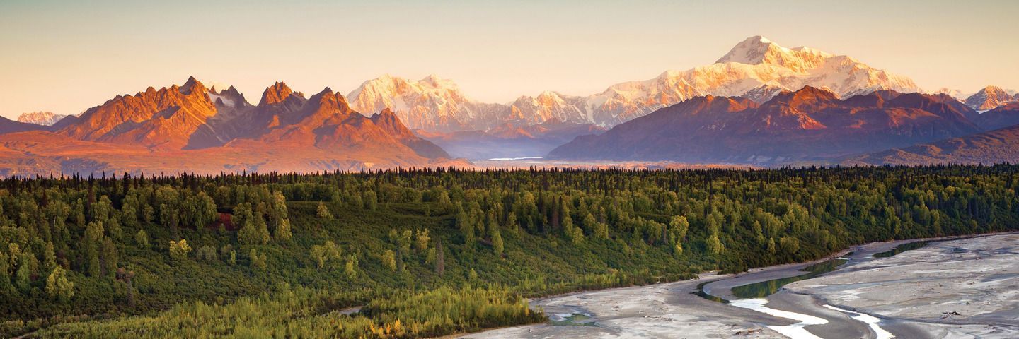 A lake with mountains in the background and trees on the shore in Alaska. 