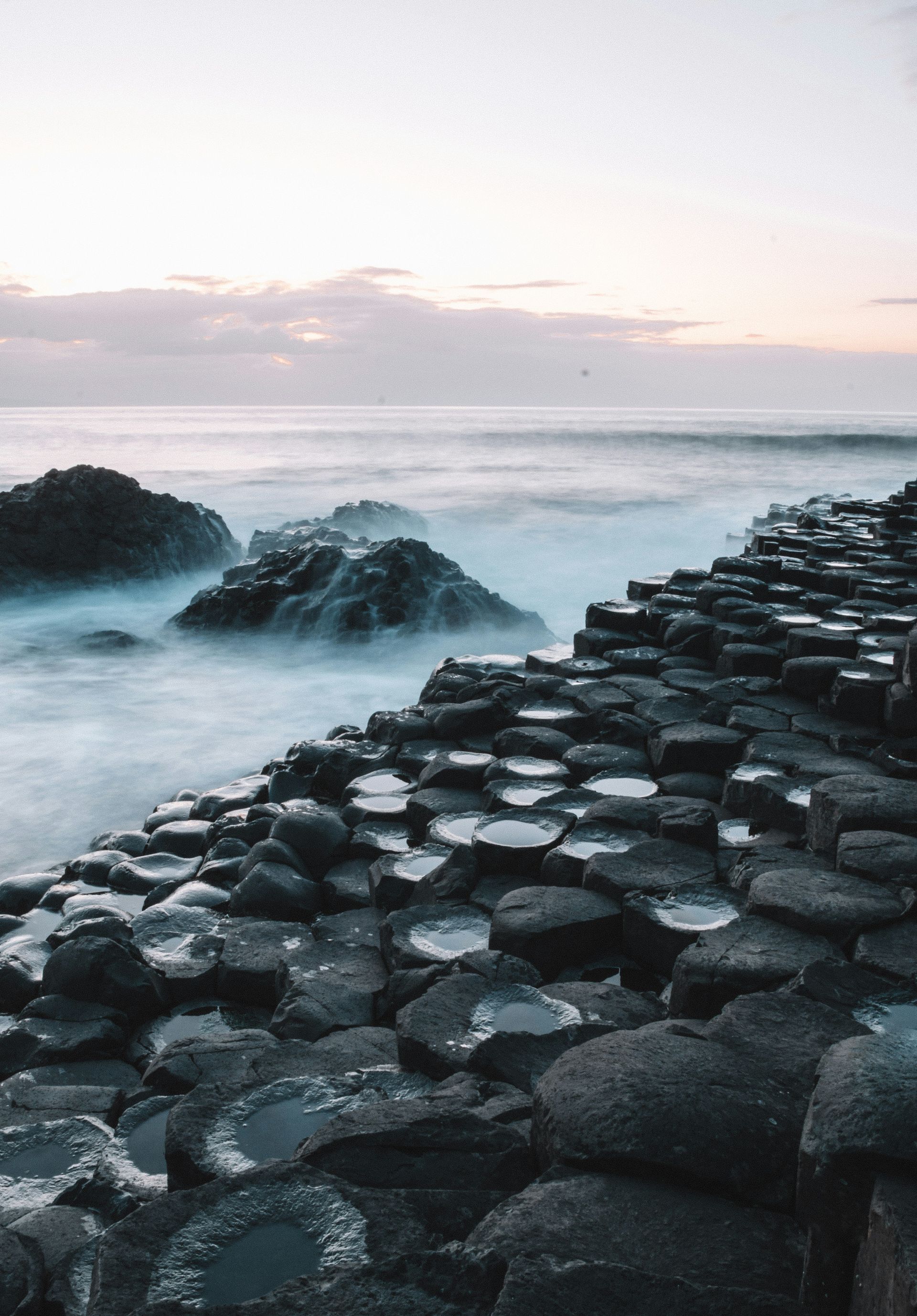 Hexagonal basalt columns meet the sea.  Waves surge against the shore at the Giant's Causeway, Northern Ireland.