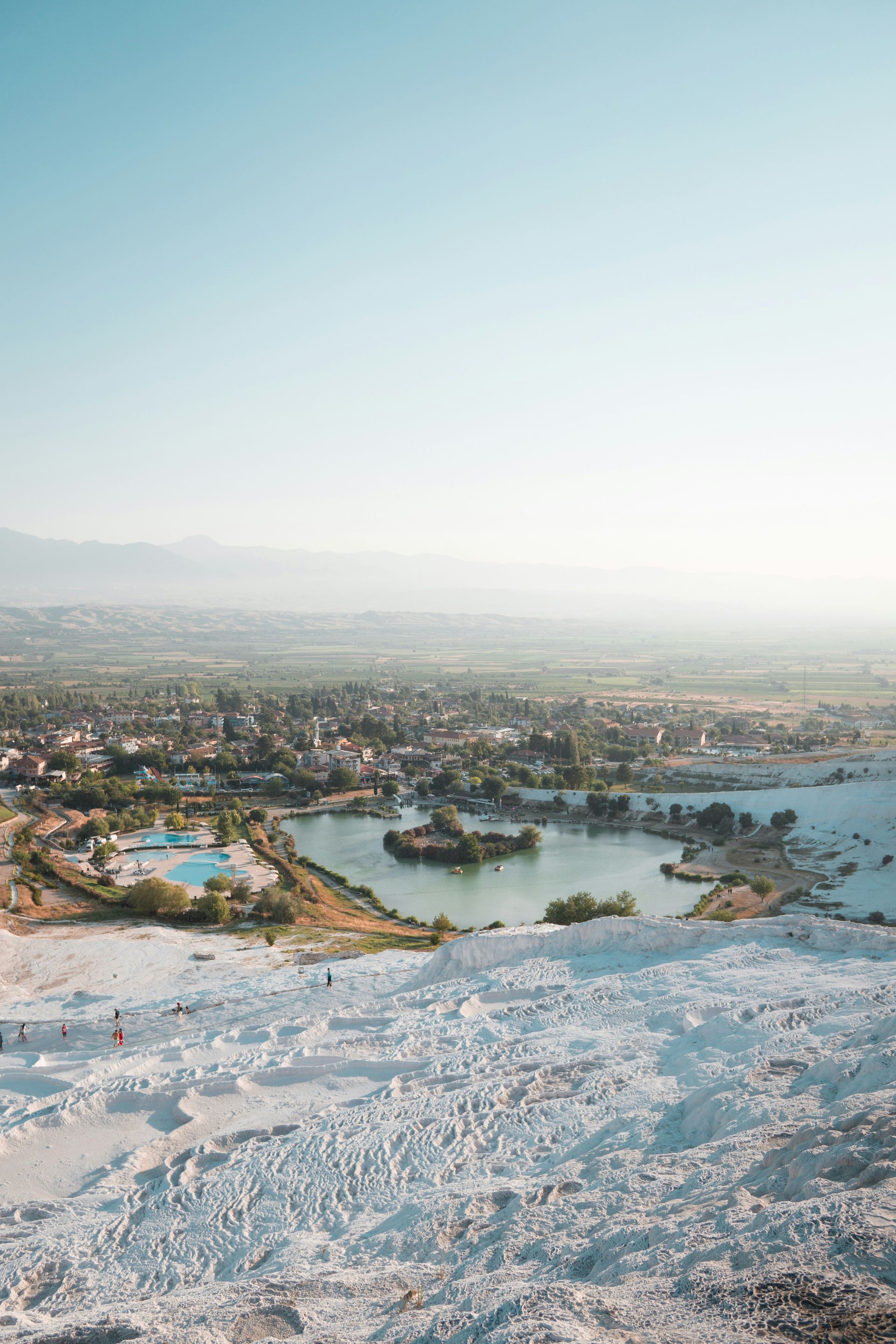 White travertine terraces overlook a town and lake in Pamukkale, Turkey.