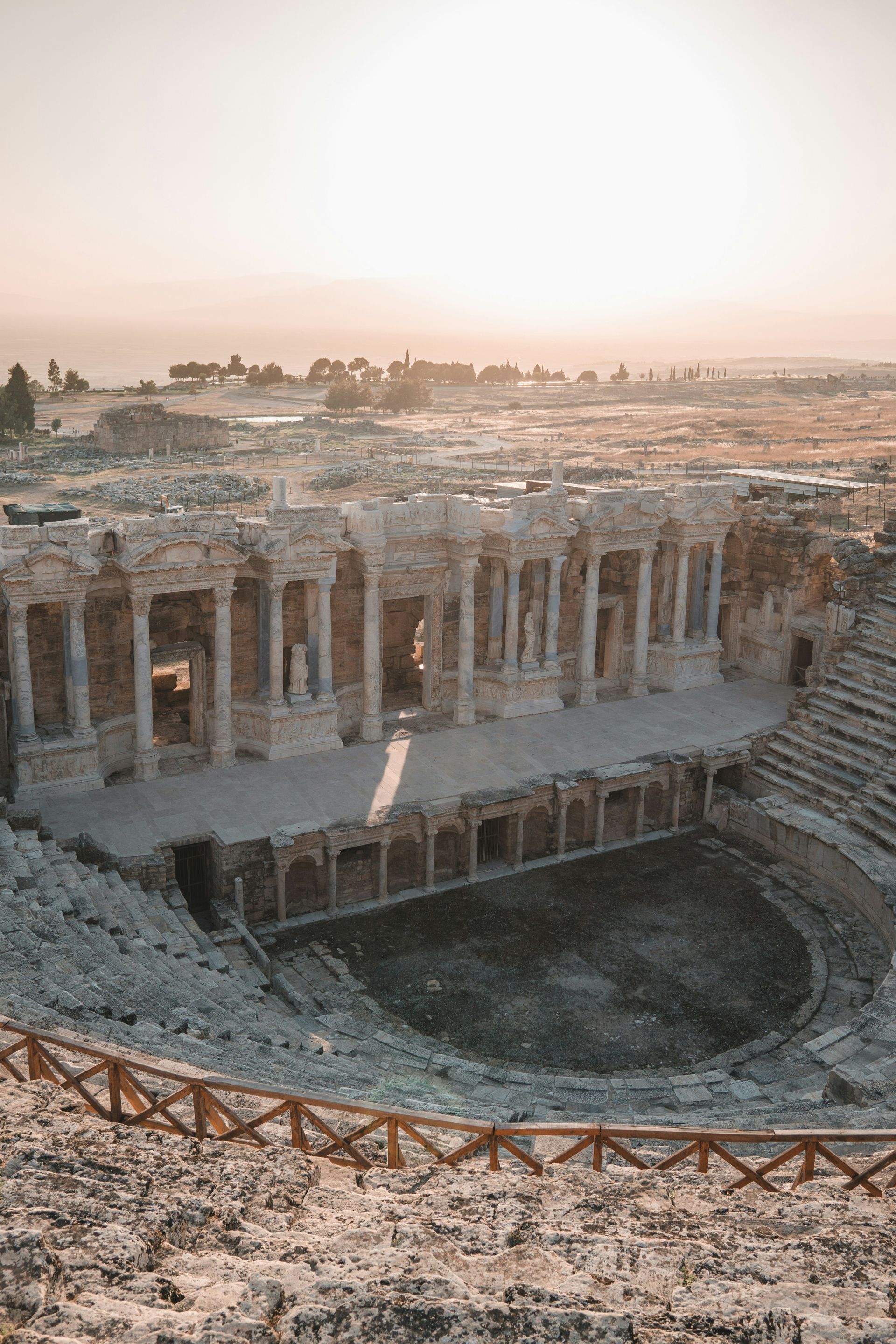 Ancient theater ruins at sunset with a wooden fence in the foreground in Pamukkale, Turkey.