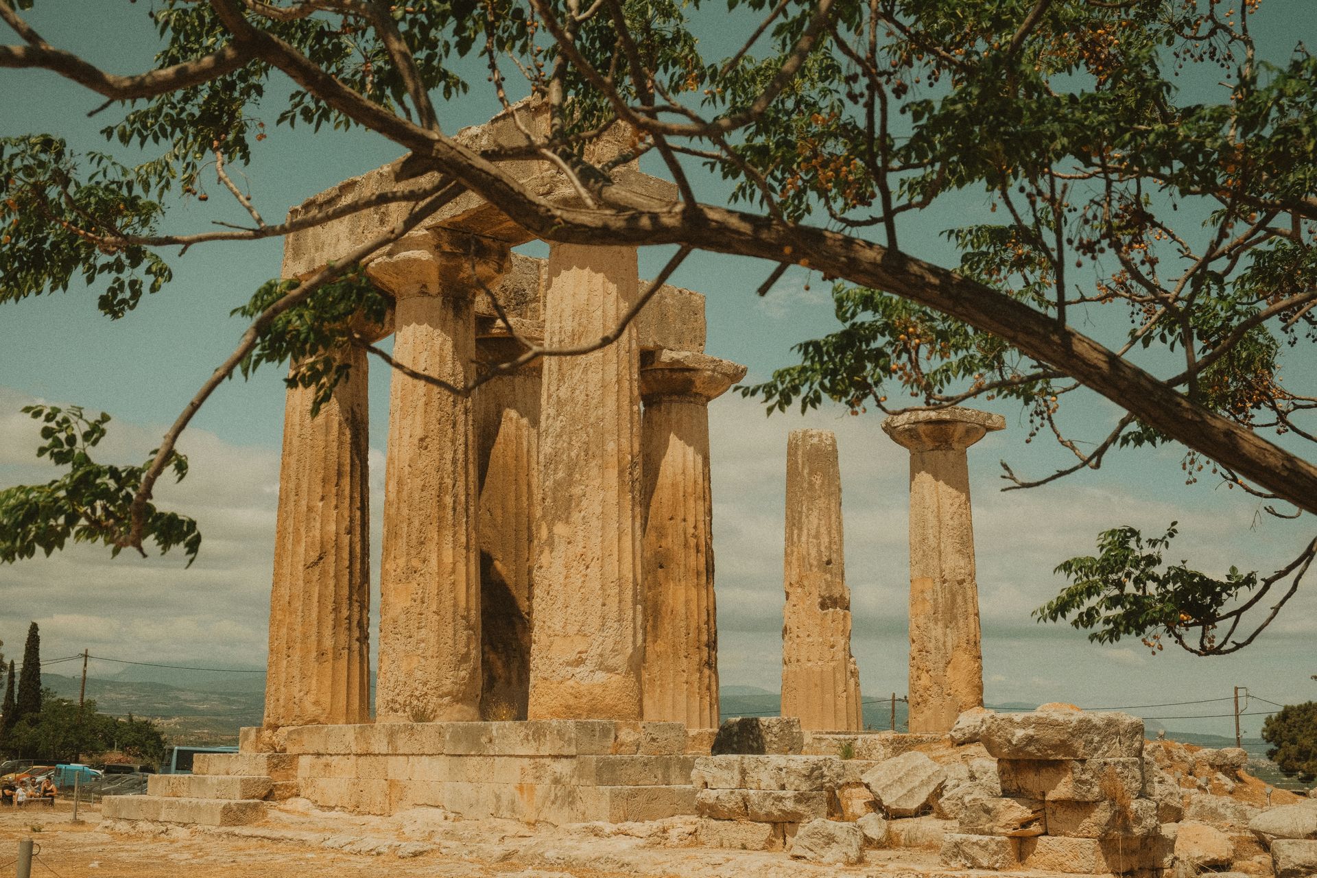 A group of ancient temples surrounded by trees on top of a hill in the Peloponnese, Greece.