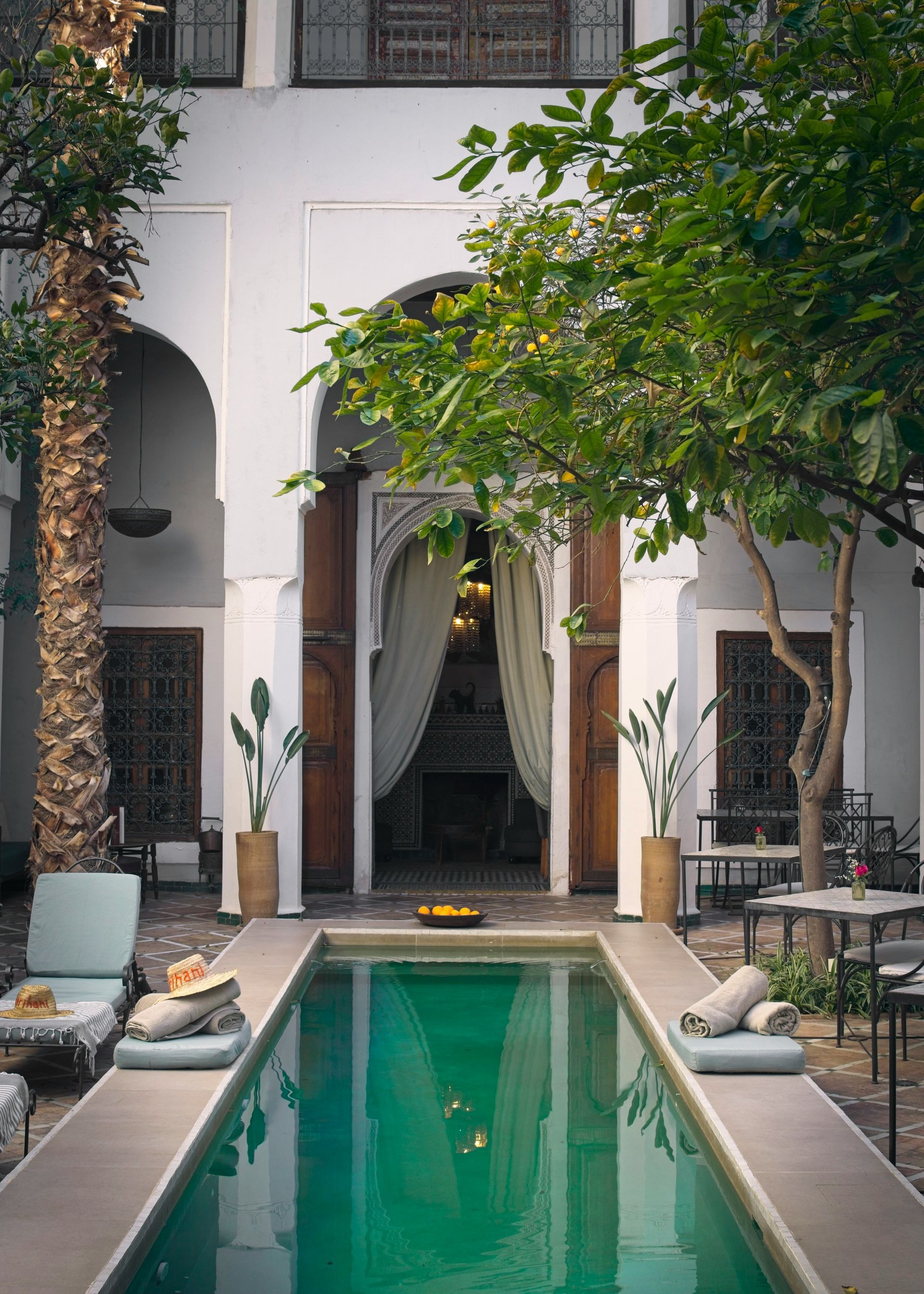 There is a large swimming pool in the middle of a courtyard in a Riad in Morocco.