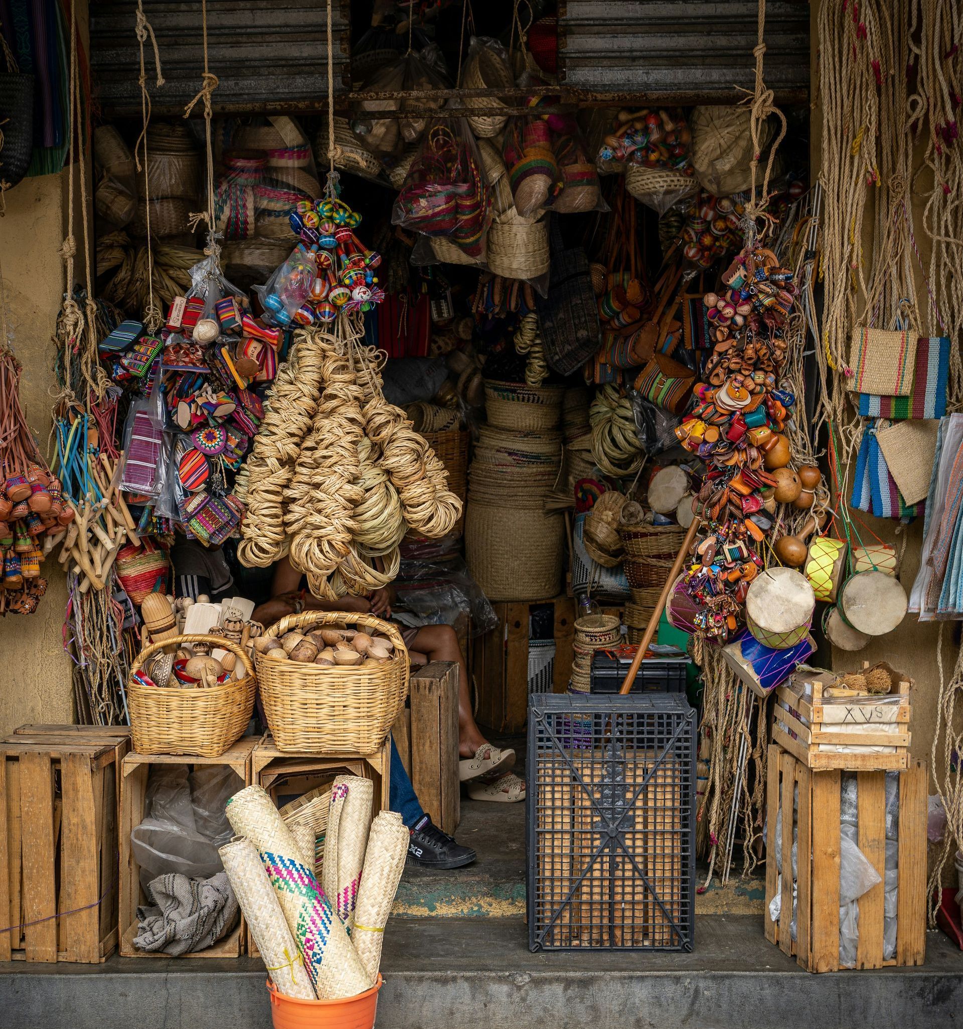 Shopfront filled with handcrafted goods: baskets, textiles, and woven items. A person sits inside the store in Mexico.