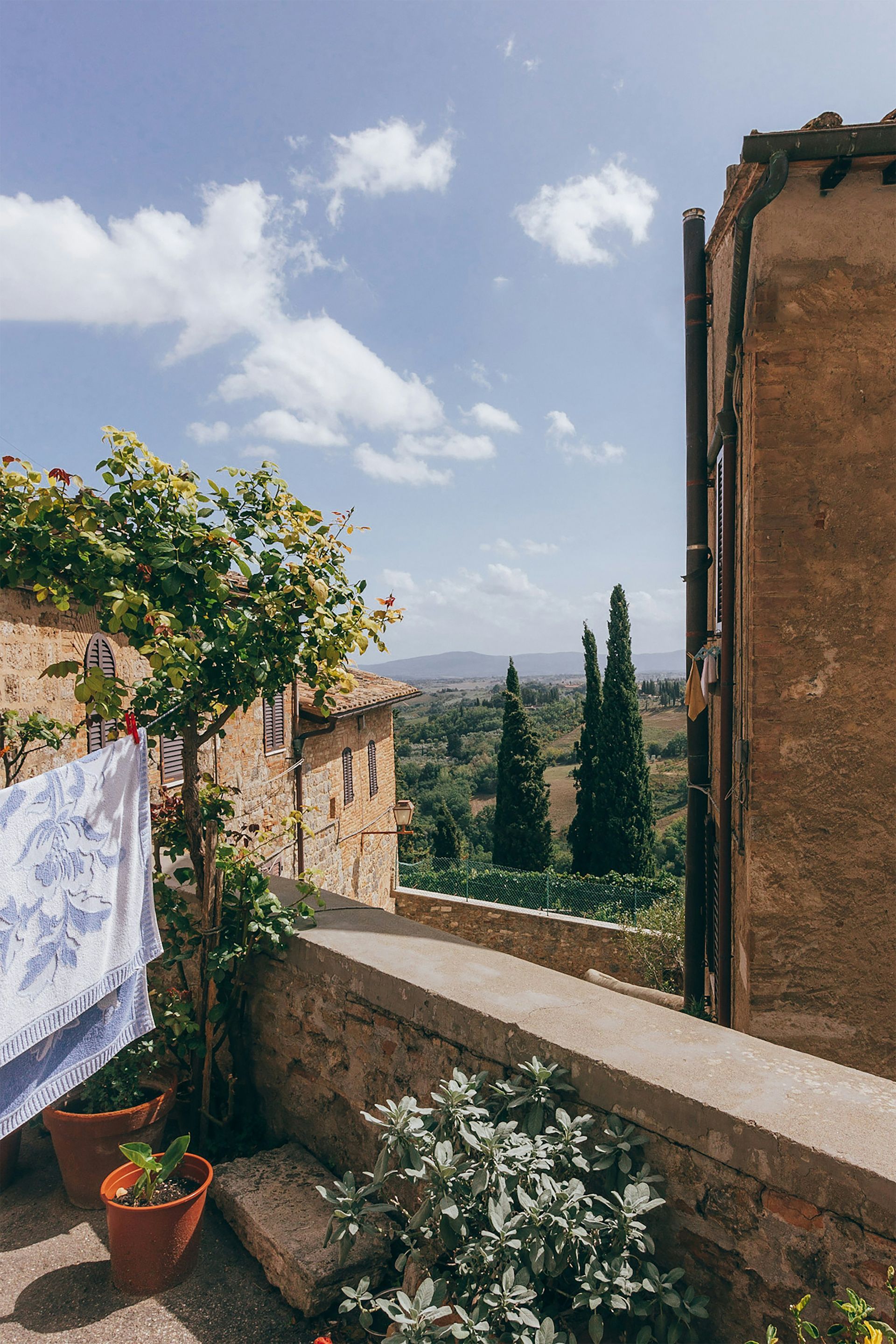 A balcony with a view of a valley and trees in Asciano, Tuscany.