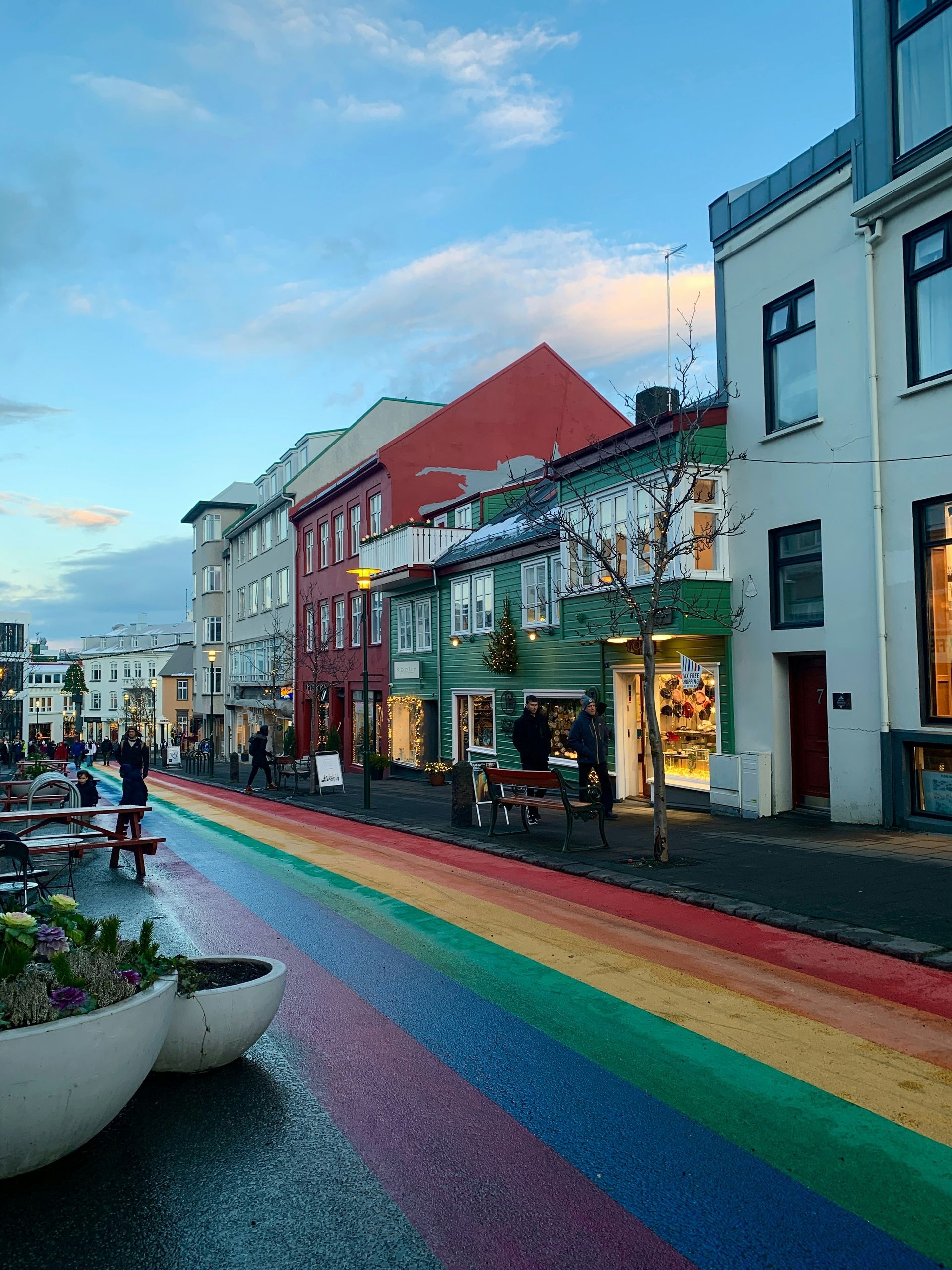 Rainbow street in Reykjavik, Iceland, lined with colorful buildings, people, and a cloudy sky.