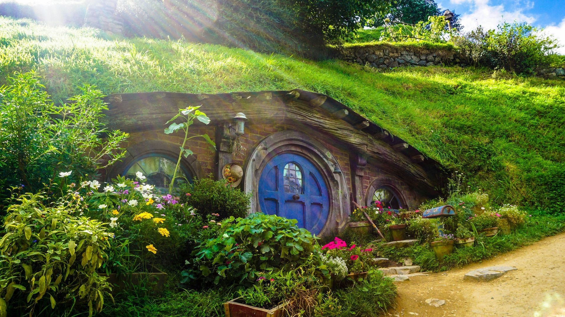 A small house with a blue door is inside a hill at the Hobbiton Movie Set in Matamata, New Zealand.