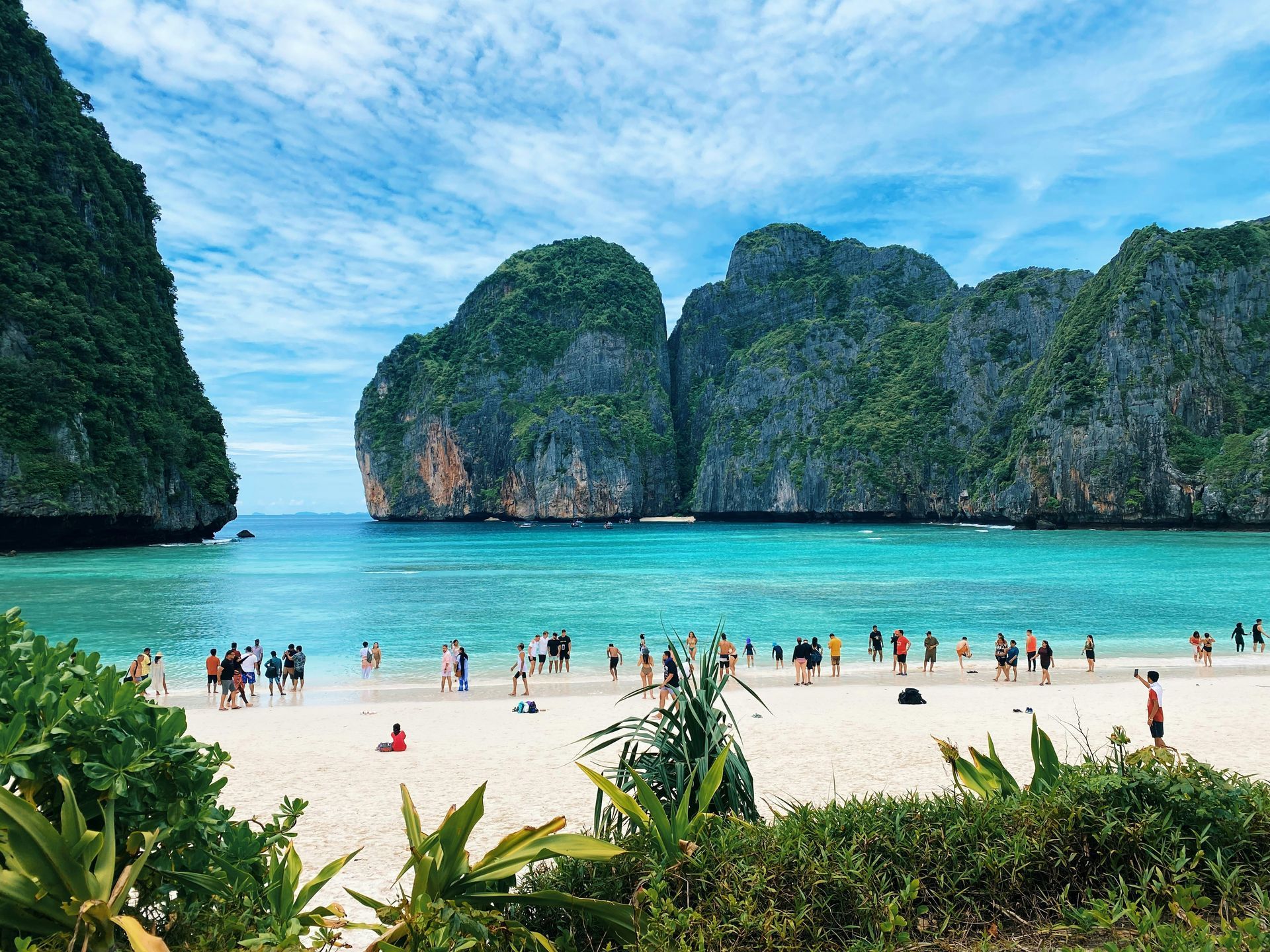 A group of people are standing on a beach near the ocean in Phuket, Thailand.