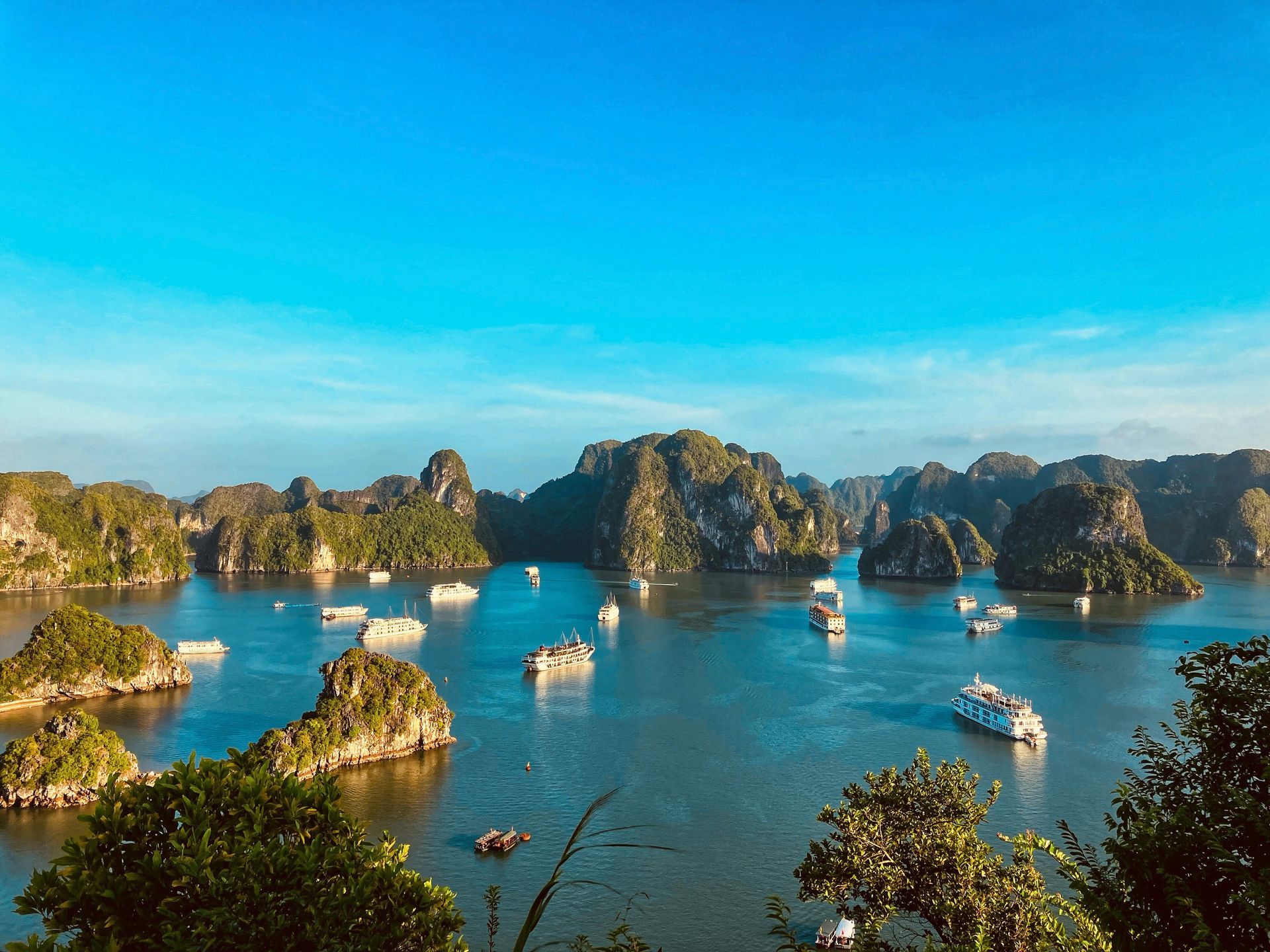 Halong Bay is dotted with limestone islands and boats, under a clear blue sky in Vietnam.