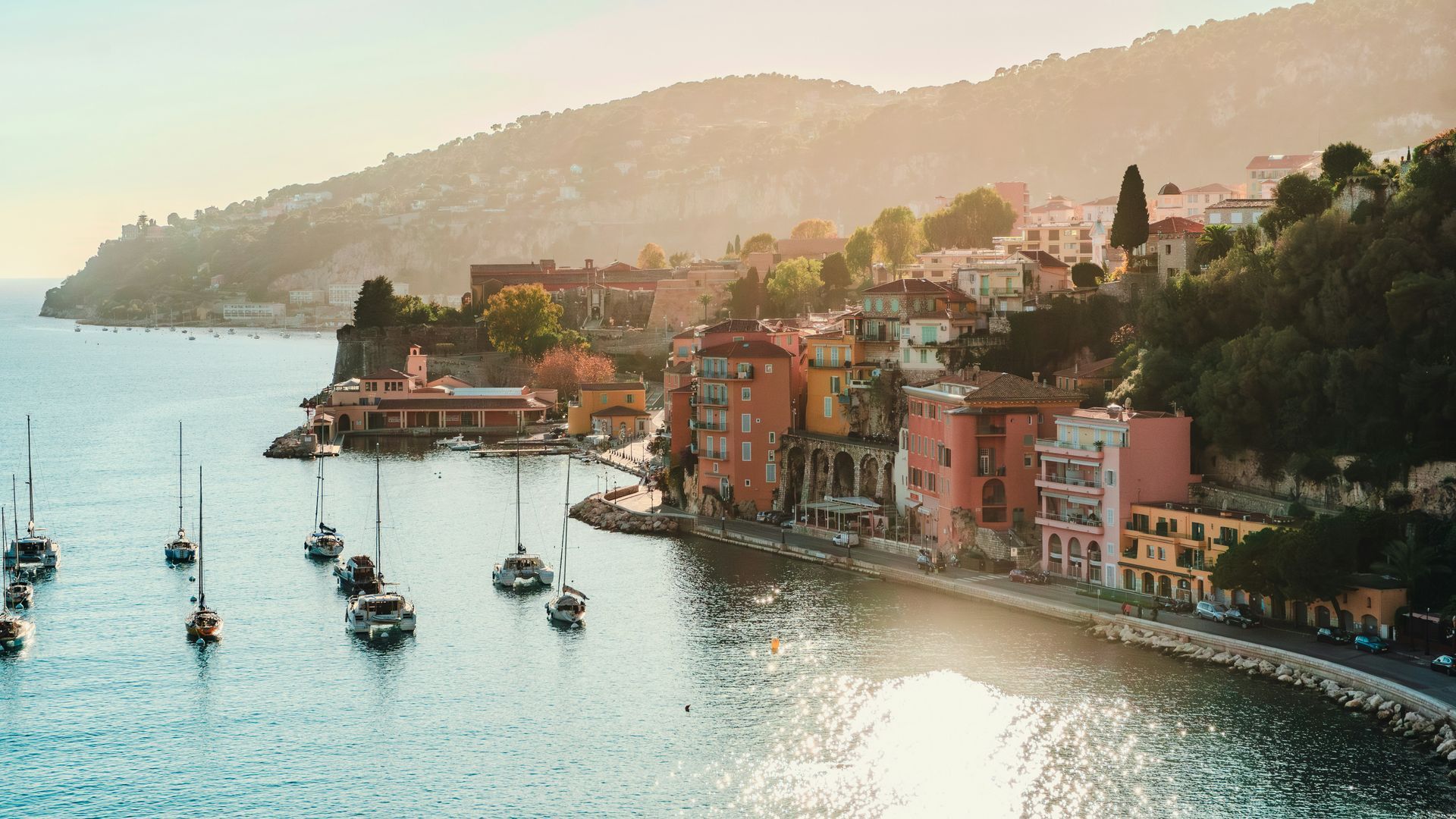 A group of boats are floating on top of a body of water next to a city on the French Riviera.