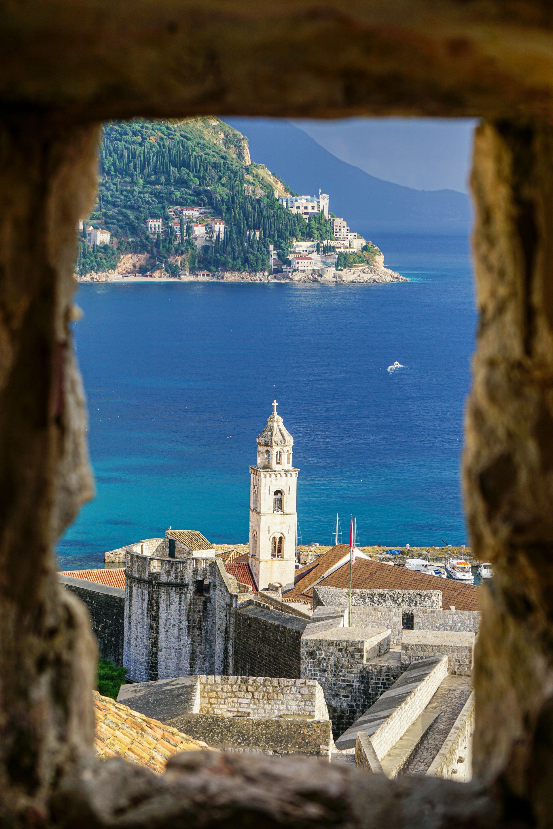 A view of a city from a window overlooking the ocean.
