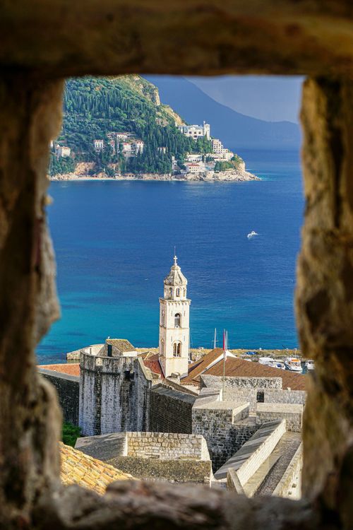 A view of a city from a window overlooking the ocean.