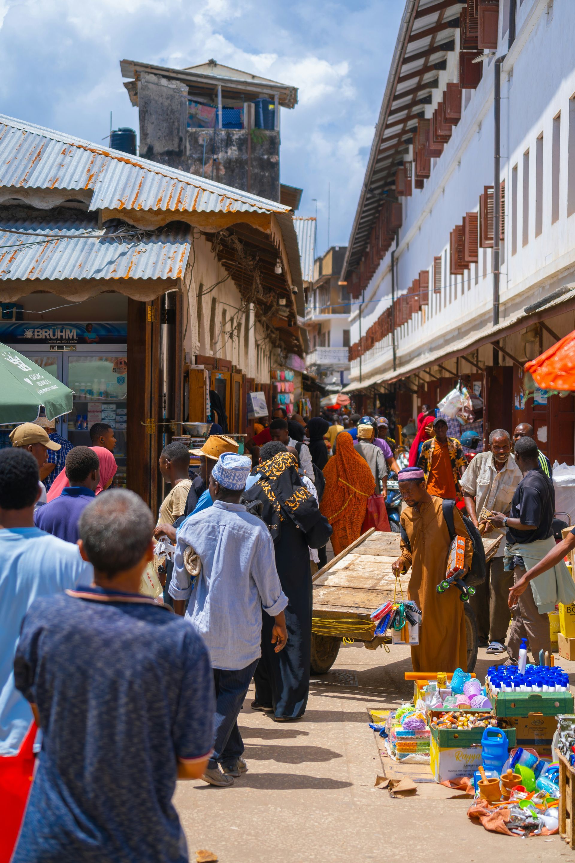 A crowd of people are walking down a street in a market in Zanzibar, Tanzania.