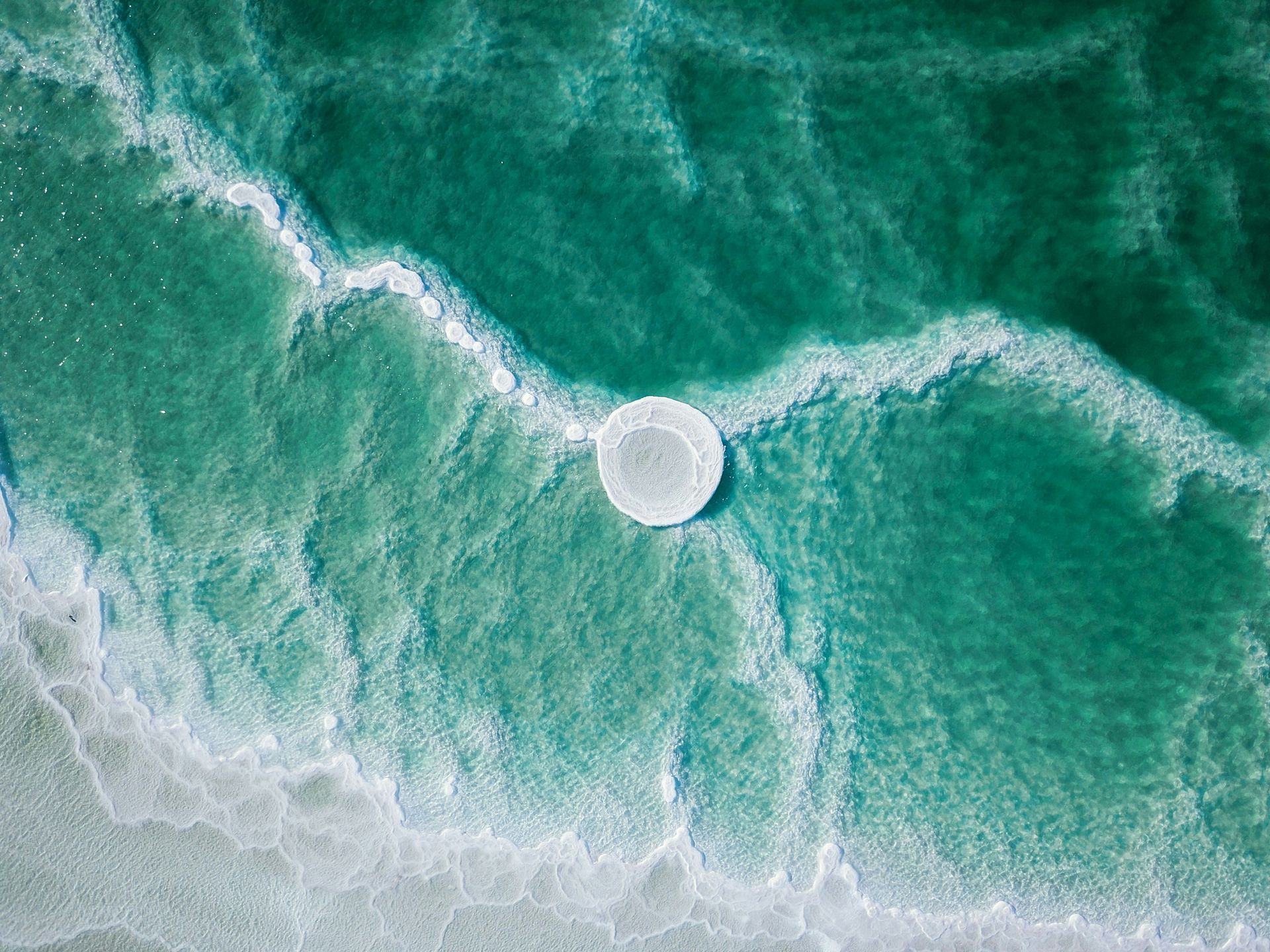 Aerial view of turquoise water and salt formations in the Dead Sea, in Jordan.