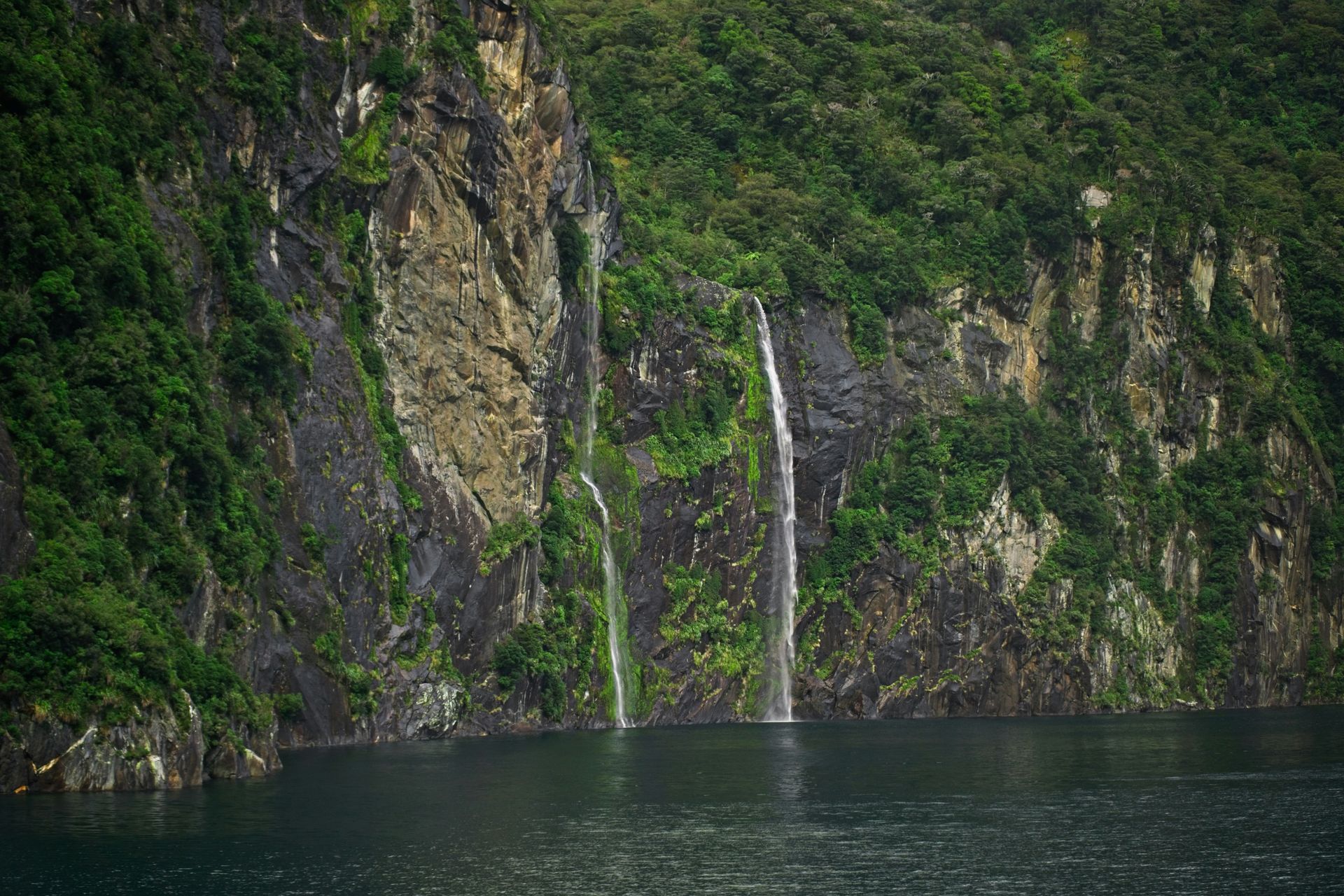There is a waterfall in the middle of the Milford Sound in Fiordland National Park, New Zealand.
