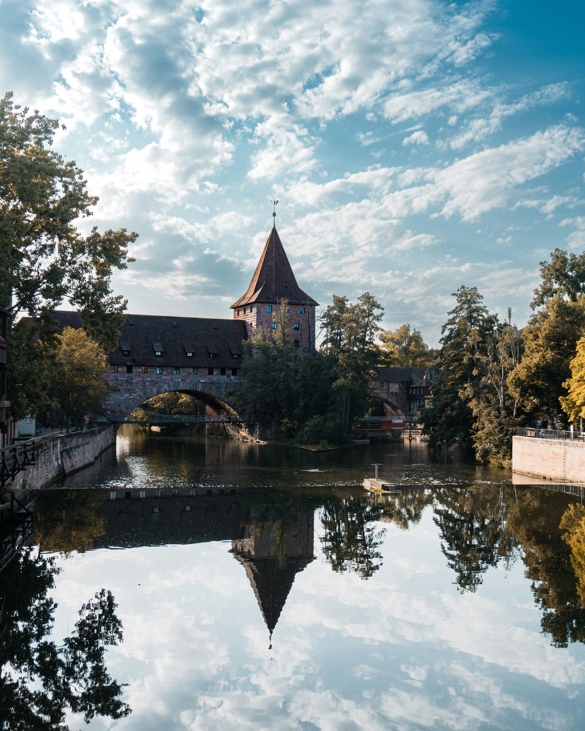 Medieval tower and bridge reflected in calm water in Nuremberg, Germany.