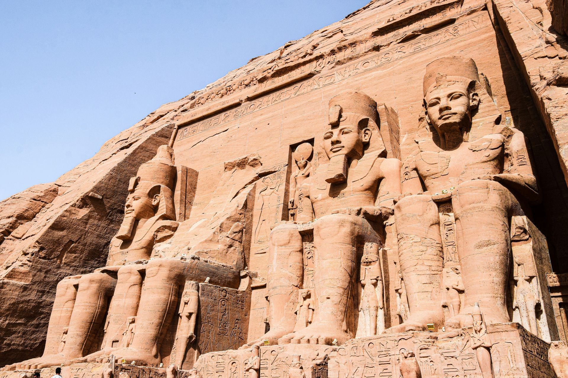 A group of statues standing next to each other in front of a building in Abu Simbel, Egypt.
