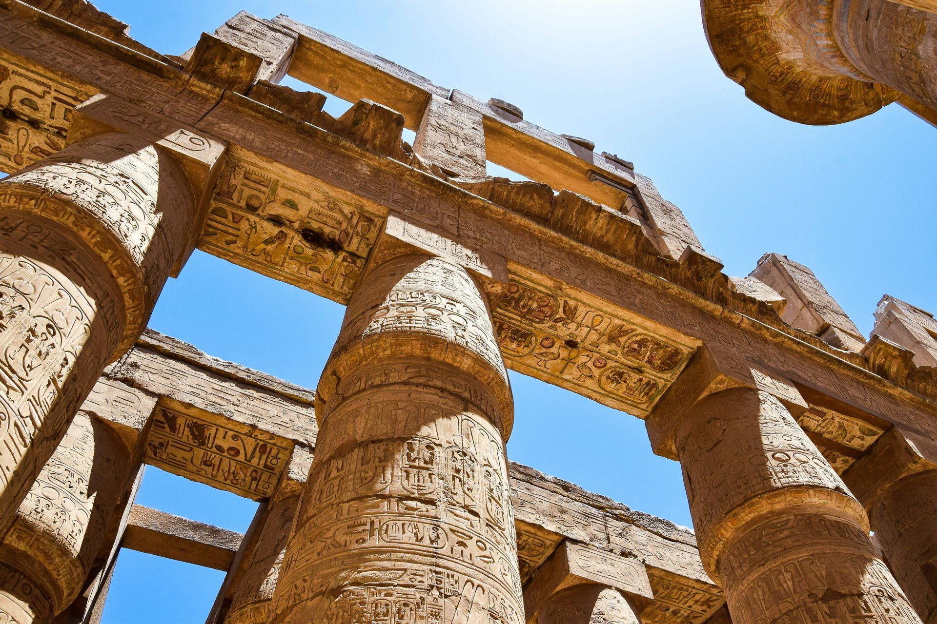 Looking up at the columns of an ancient building with a blue sky in the background in Luxor, Egypt.
