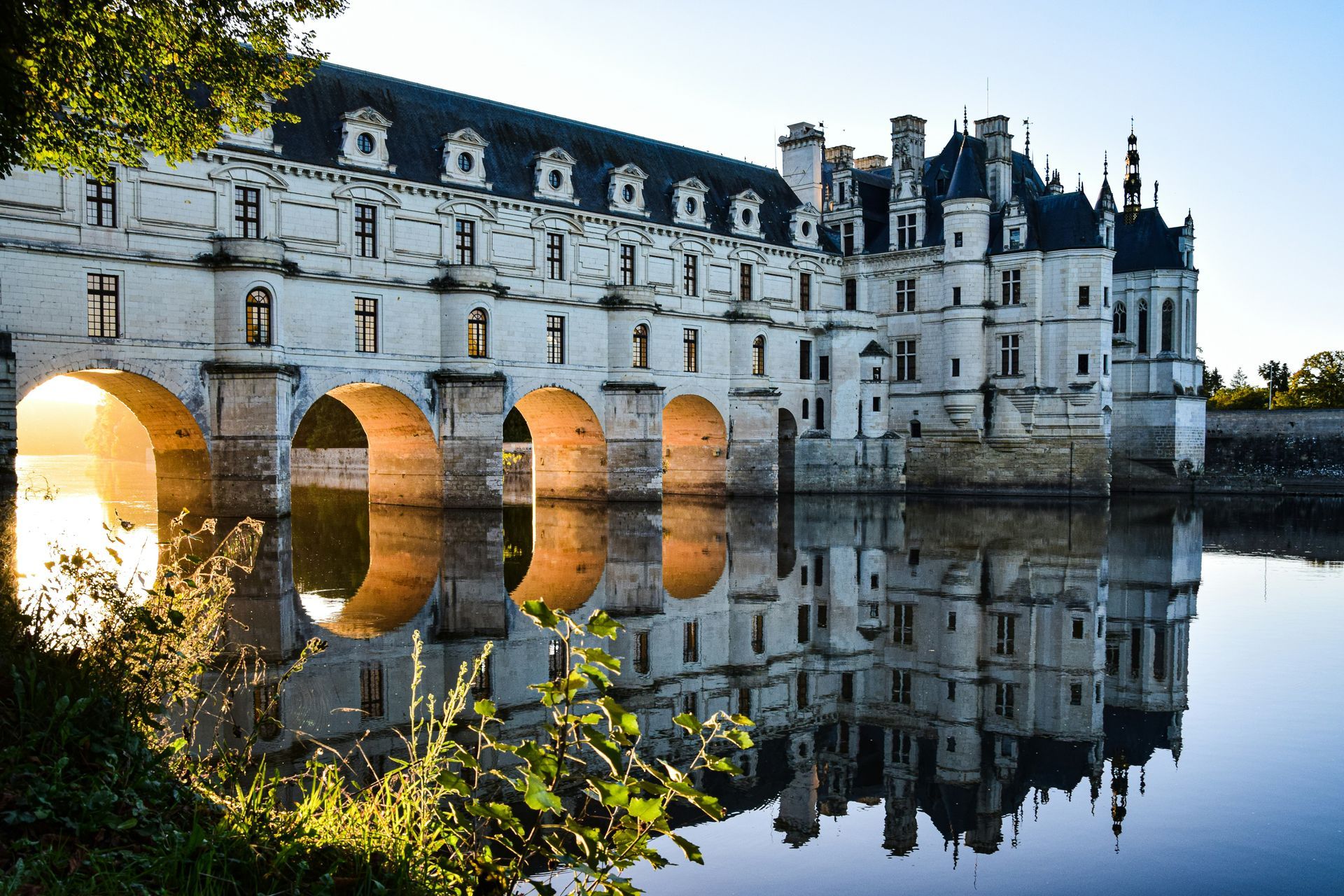 A bridge over a body of water with the Château de Chenonceau
 in the background in France.