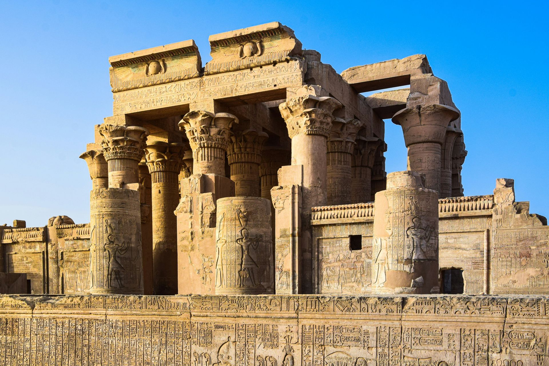 A very old building with columns and a blue sky in the background in Kom Ombo, Egypt.