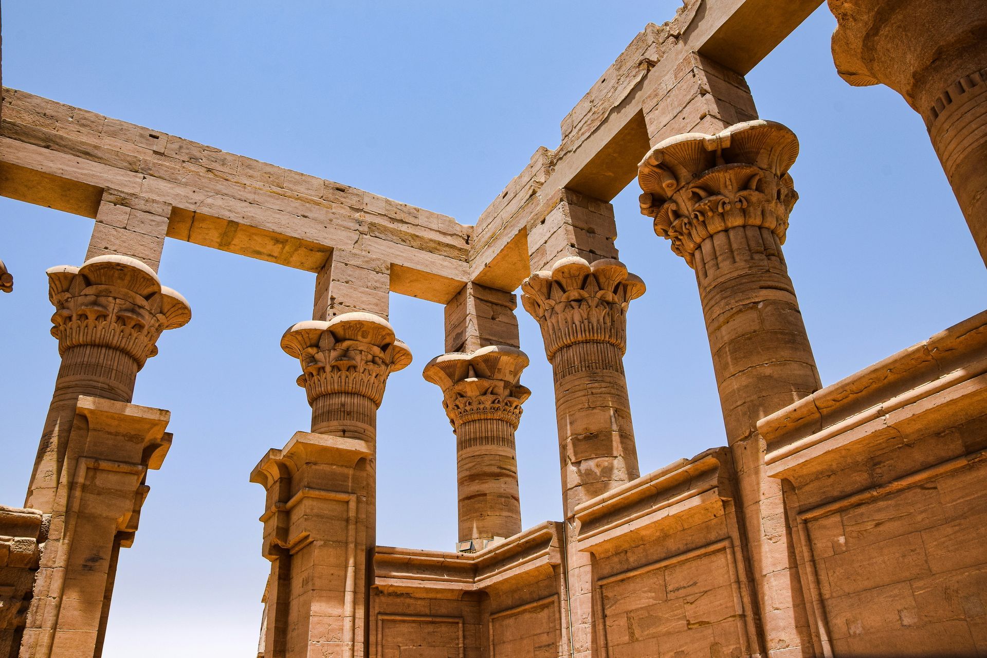 A row of columns in a building with a blue sky in the background in Aswan, Egypt.