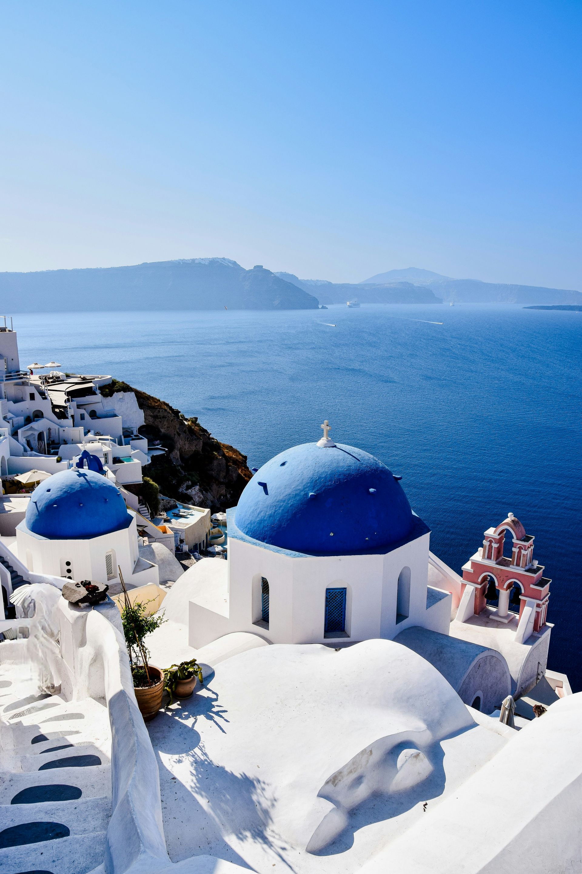 A white village with blue dome roofs overlooking the ocean in Santorini, Greece.