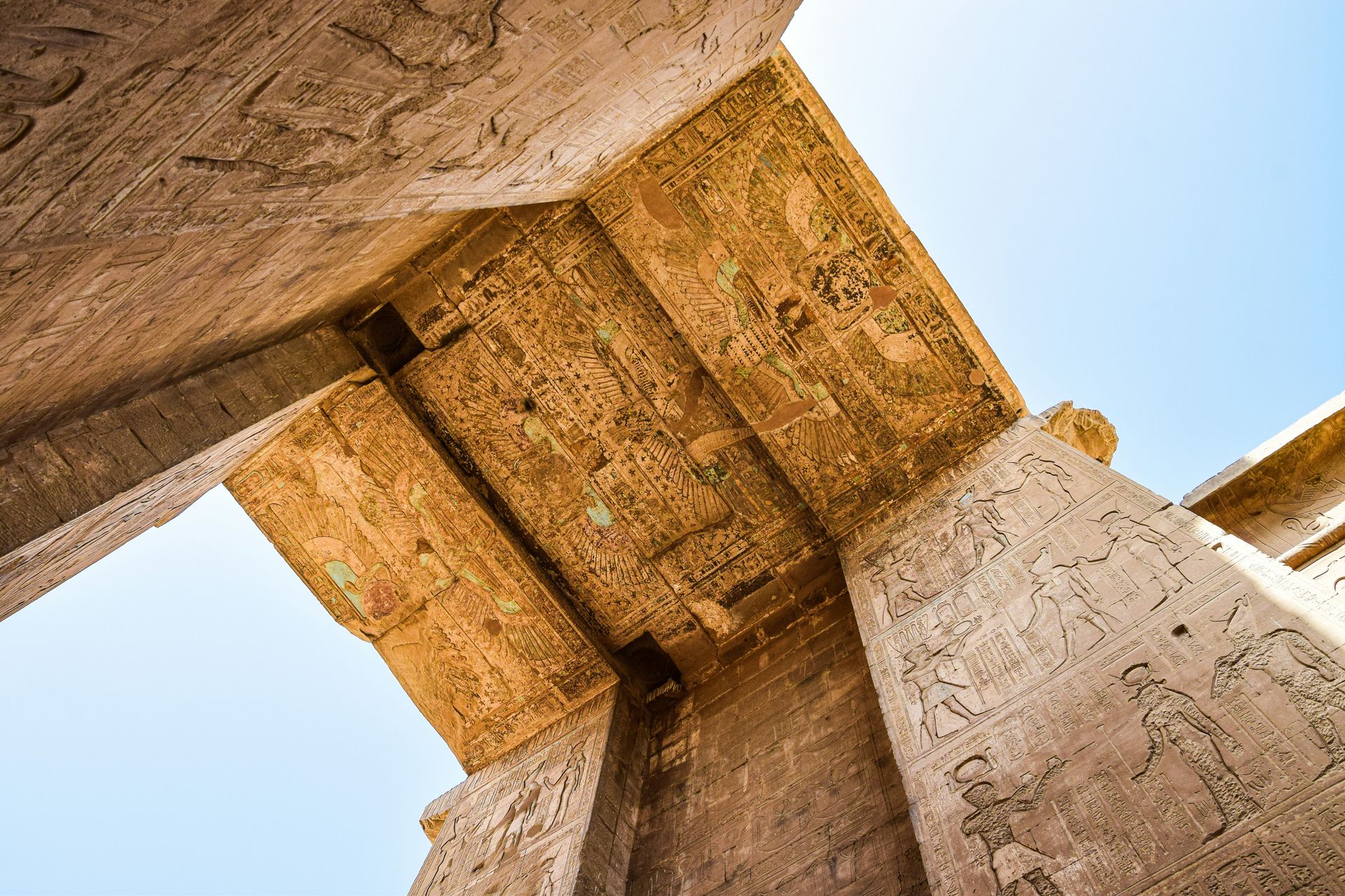 Looking up at the pillars of an ancient building filled with hieroglyphics in Kom Ombo, Egypt.