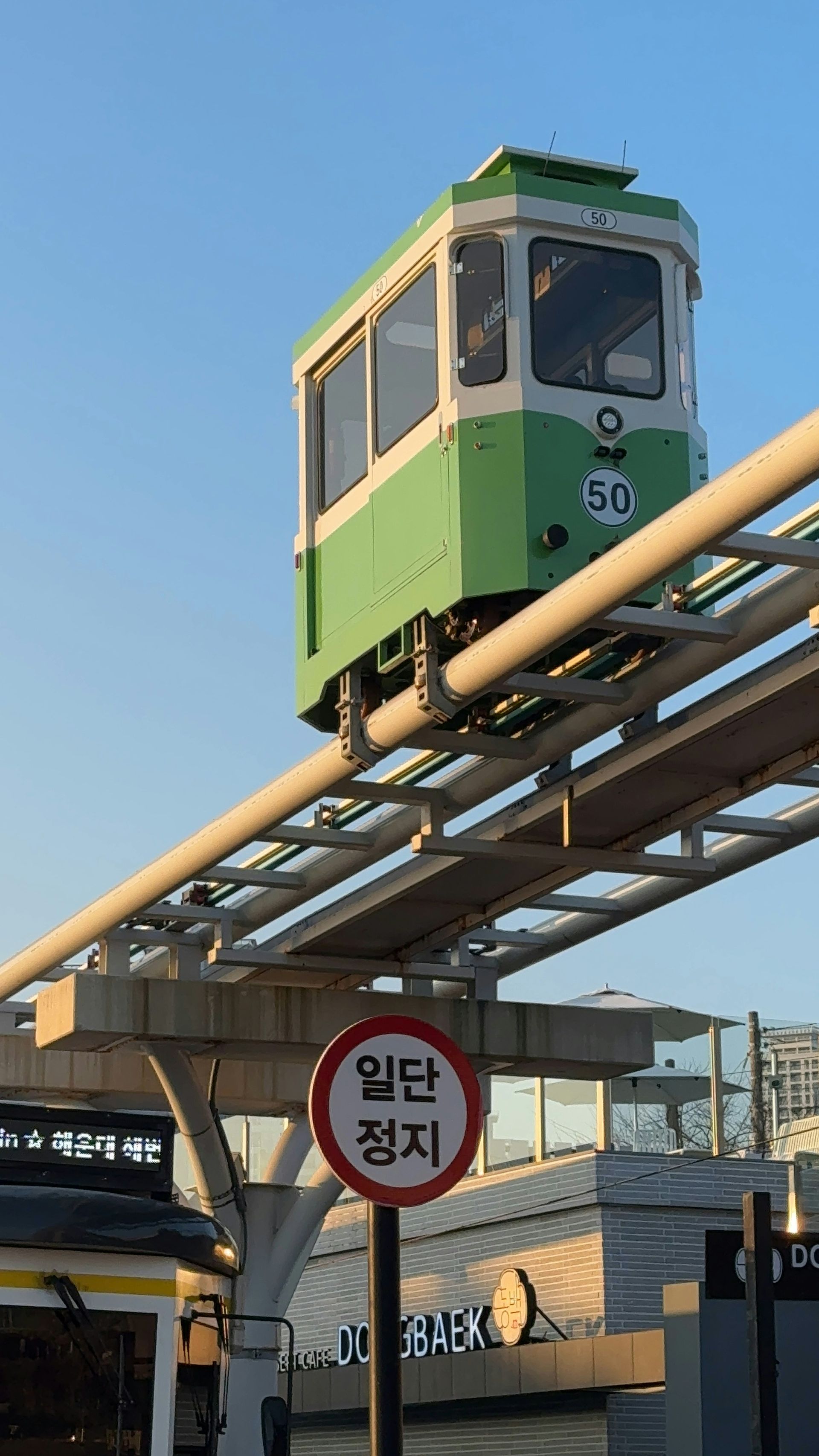 Green and white monorail car on an elevated track in Busan, South Korea.