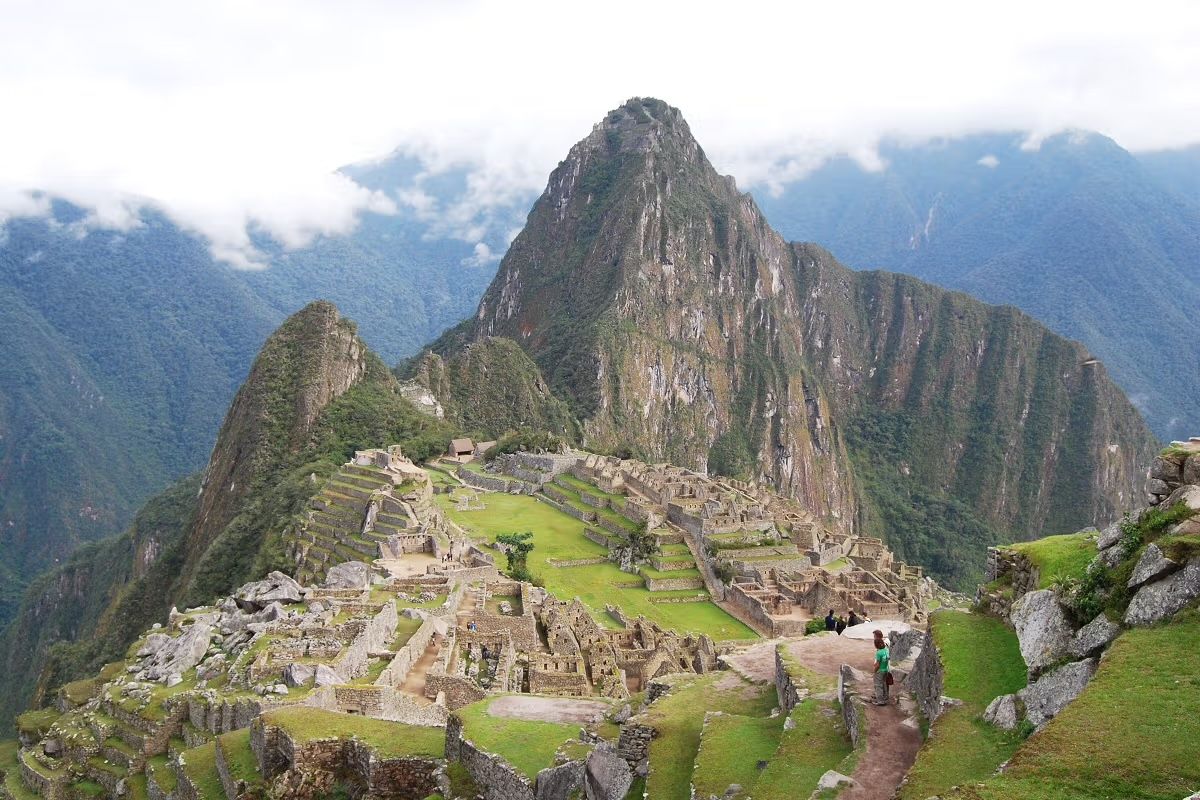 A mountain with a ruined city on top of it surrounded by mountains.