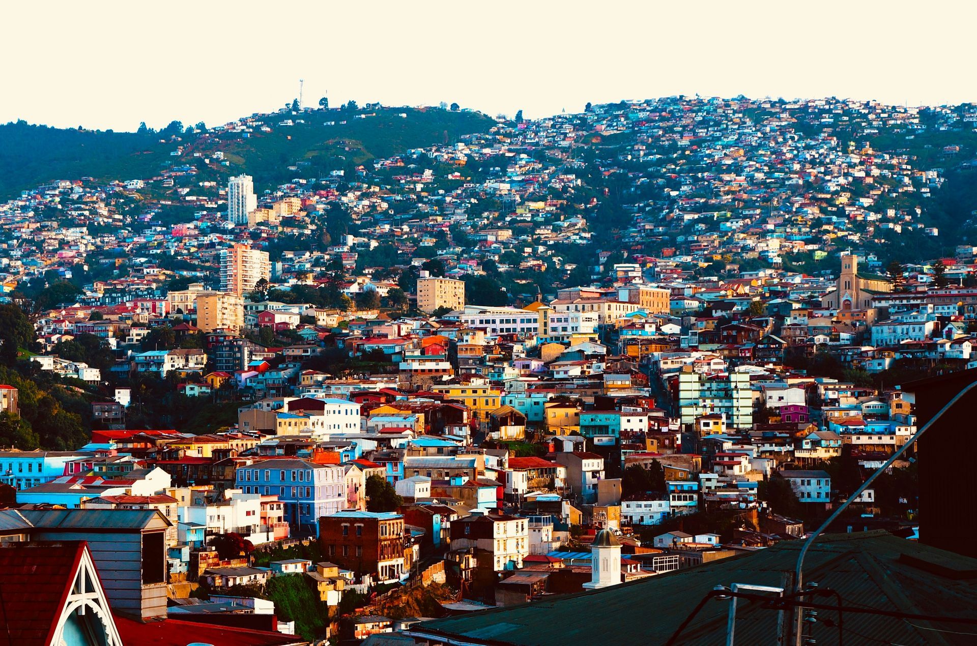 Colorful city of Valparaíso, Chile nestled on a hillside, buildings tightly packed together, under a cloudy sky.