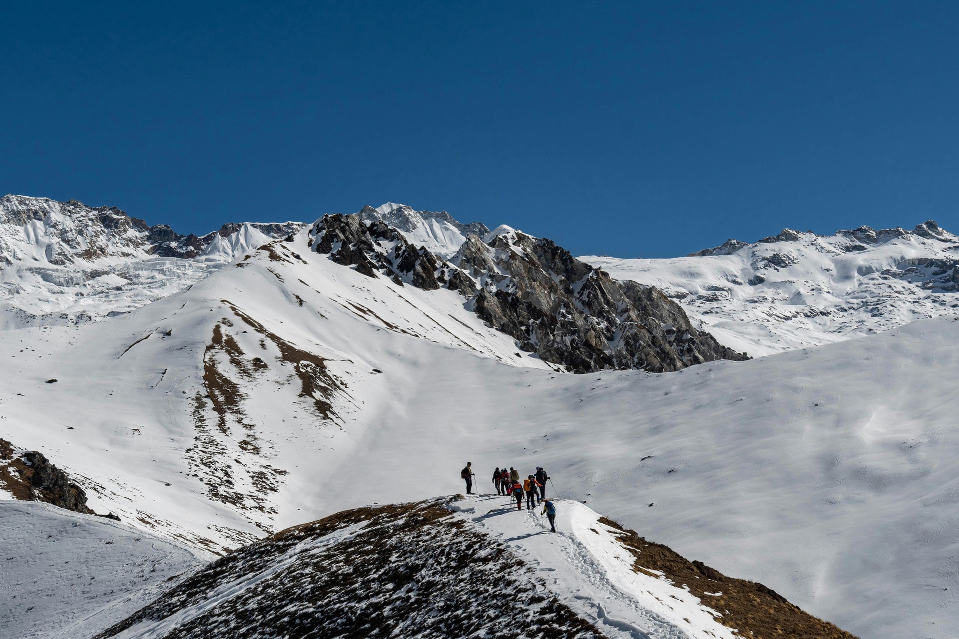 Snowy mountain range with hikers on a ridge in Langtang, Nepal.