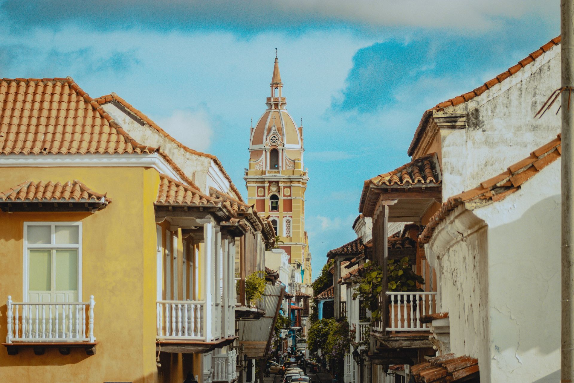 A narrow street with a clock tower in the background in Cartagena, Colombia.