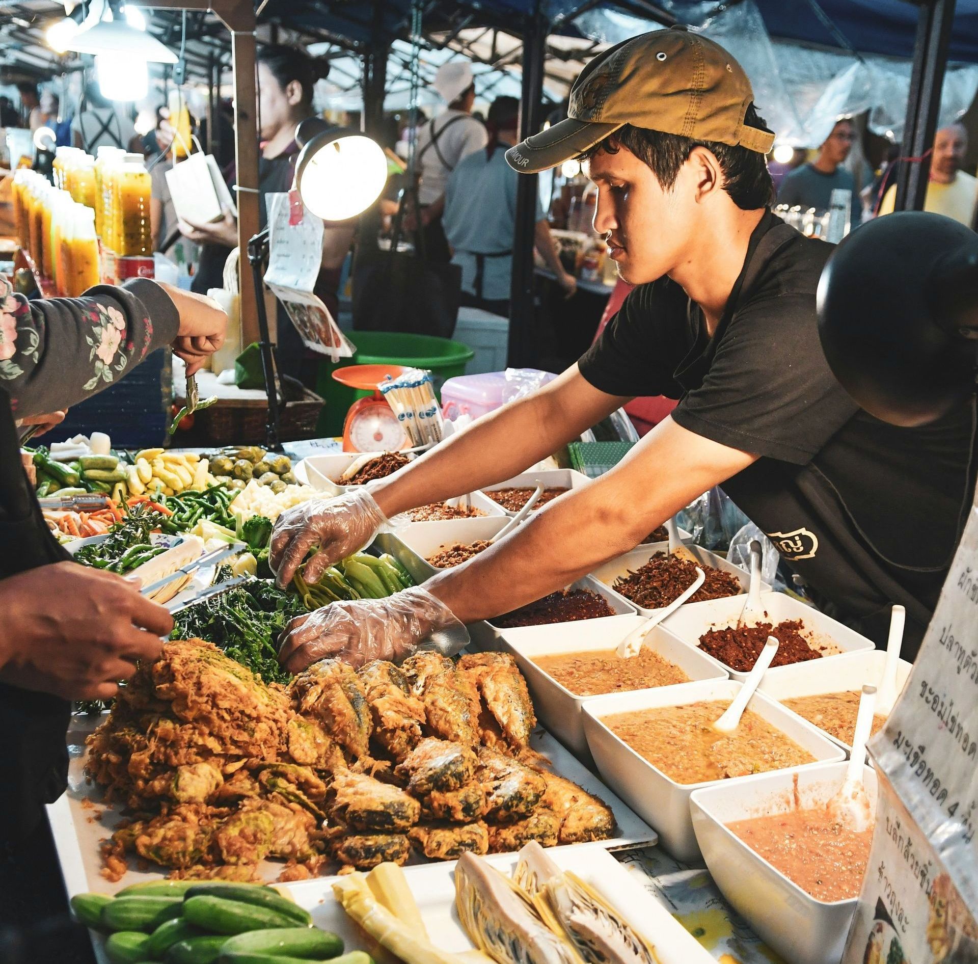 A man is preparing food at a market in Thailand.