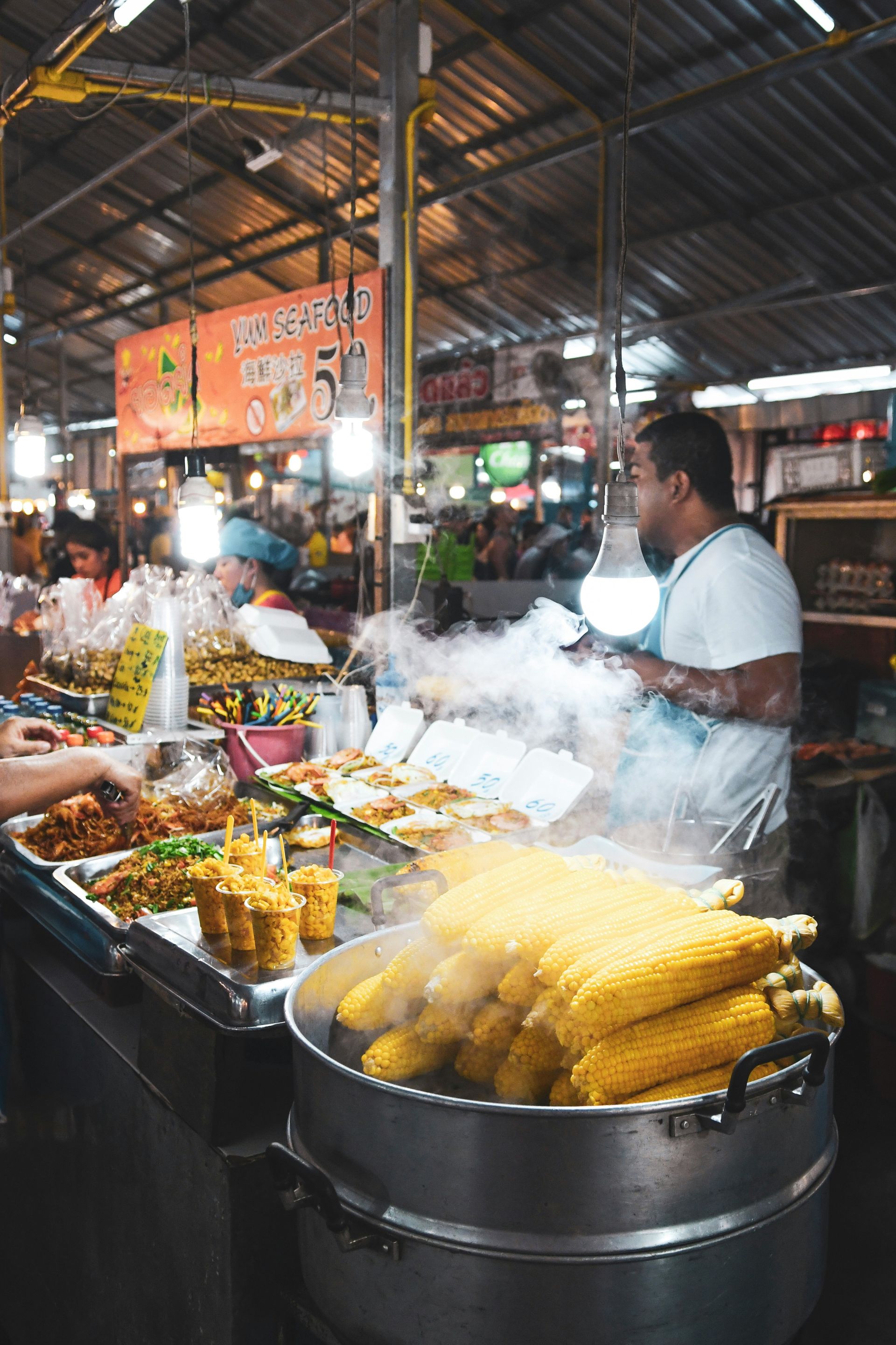 A man is cooking corn on the cob at a market in Phuket, Thailand.