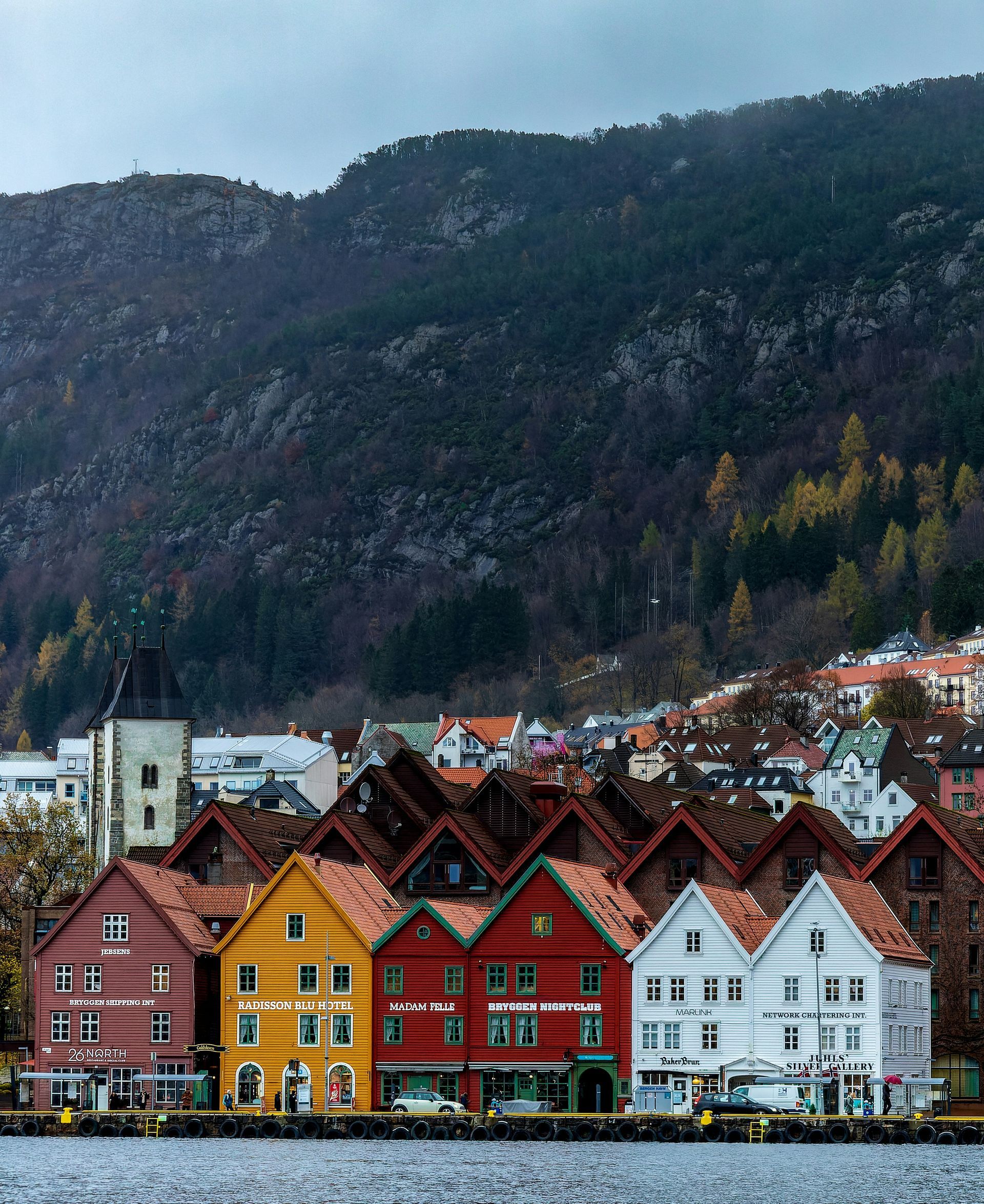 A row of houses on the shore of a lake with mountains in the background Bergen, Norway.