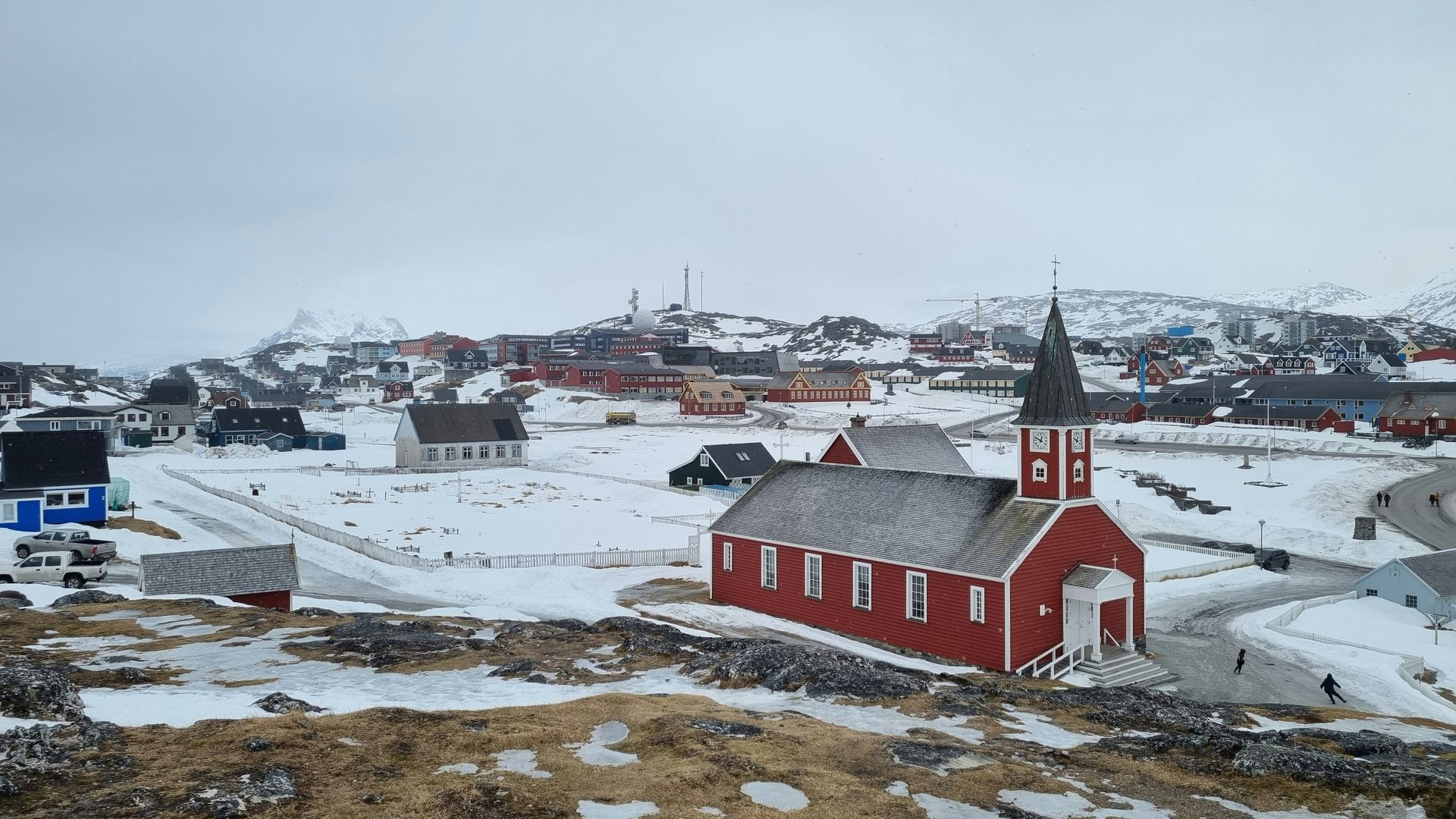 Red church in a snow-covered Greenlandic town, surrounded by buildings in Nuuk, Greenland.