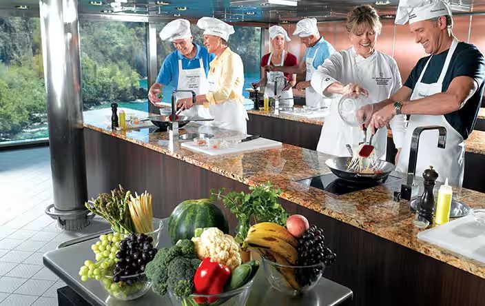 A group of people are preparing food in a kitchen on the Oceania Marina cruise ship.