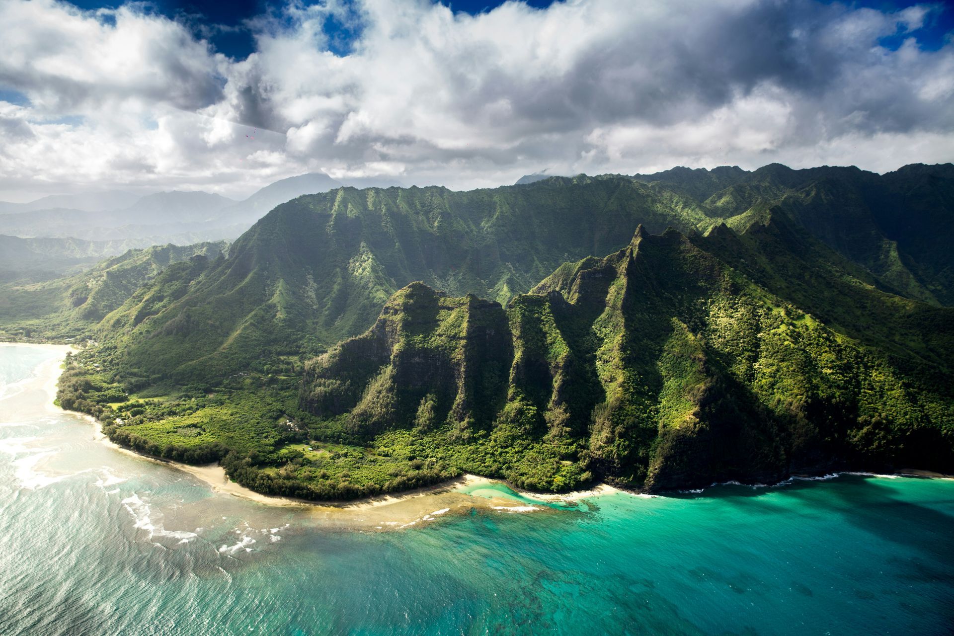 An aerial view of a tropical island with mountains and a body of water in Hawaii.