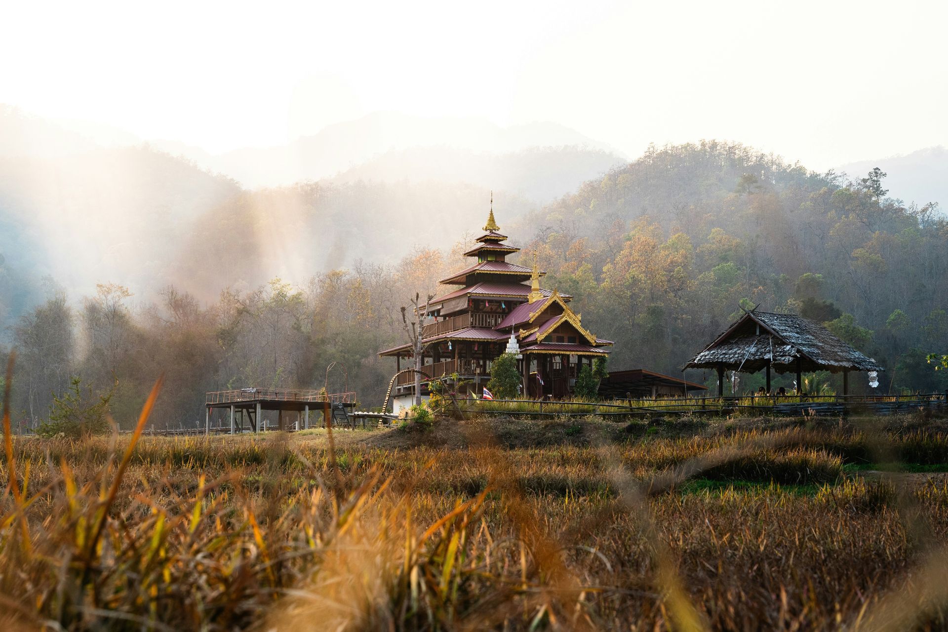 A temple is sitting on top of a hill in the middle of a field in Pai, Thailand.