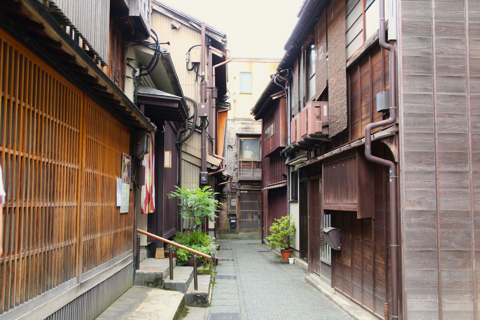 Narrow alleyway lined with traditional wooden buildings, in muted brown tones in Kanazawa, Japan.