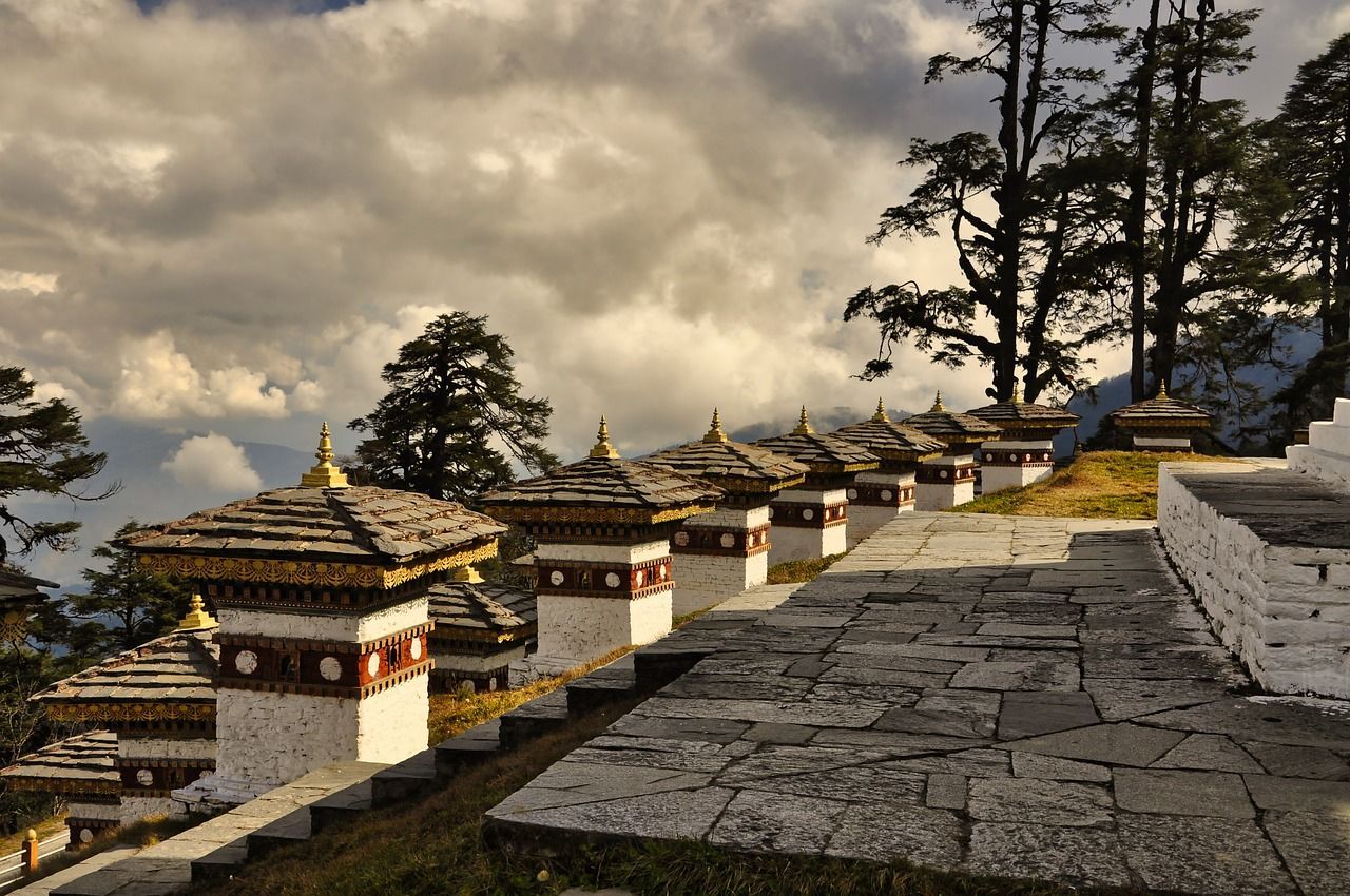 A row of small buildings on a hillside with trees in the background in Bhutan.