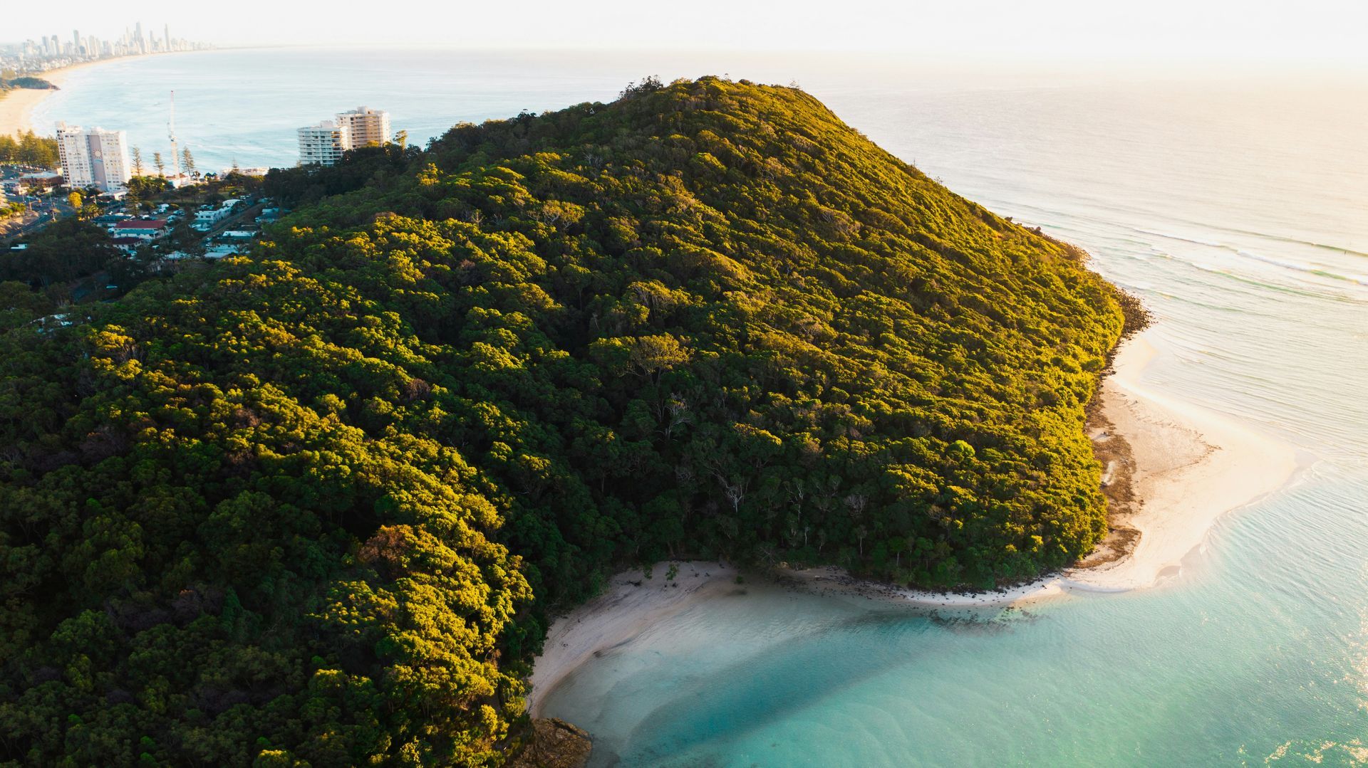 An aerial view of a small island in the middle of the ocean surrounded by trees in Gold Coast, Australia.