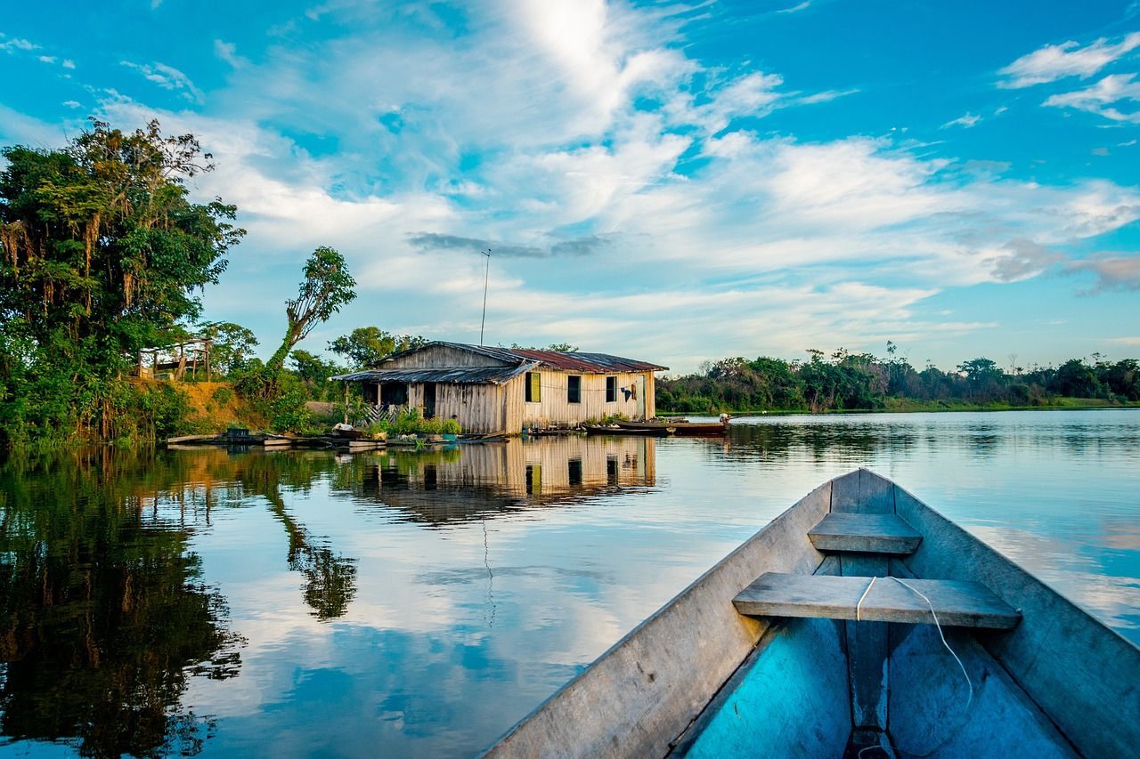 A boat is floating on a lake with a house in the background in the amazon rainforest in Peru.