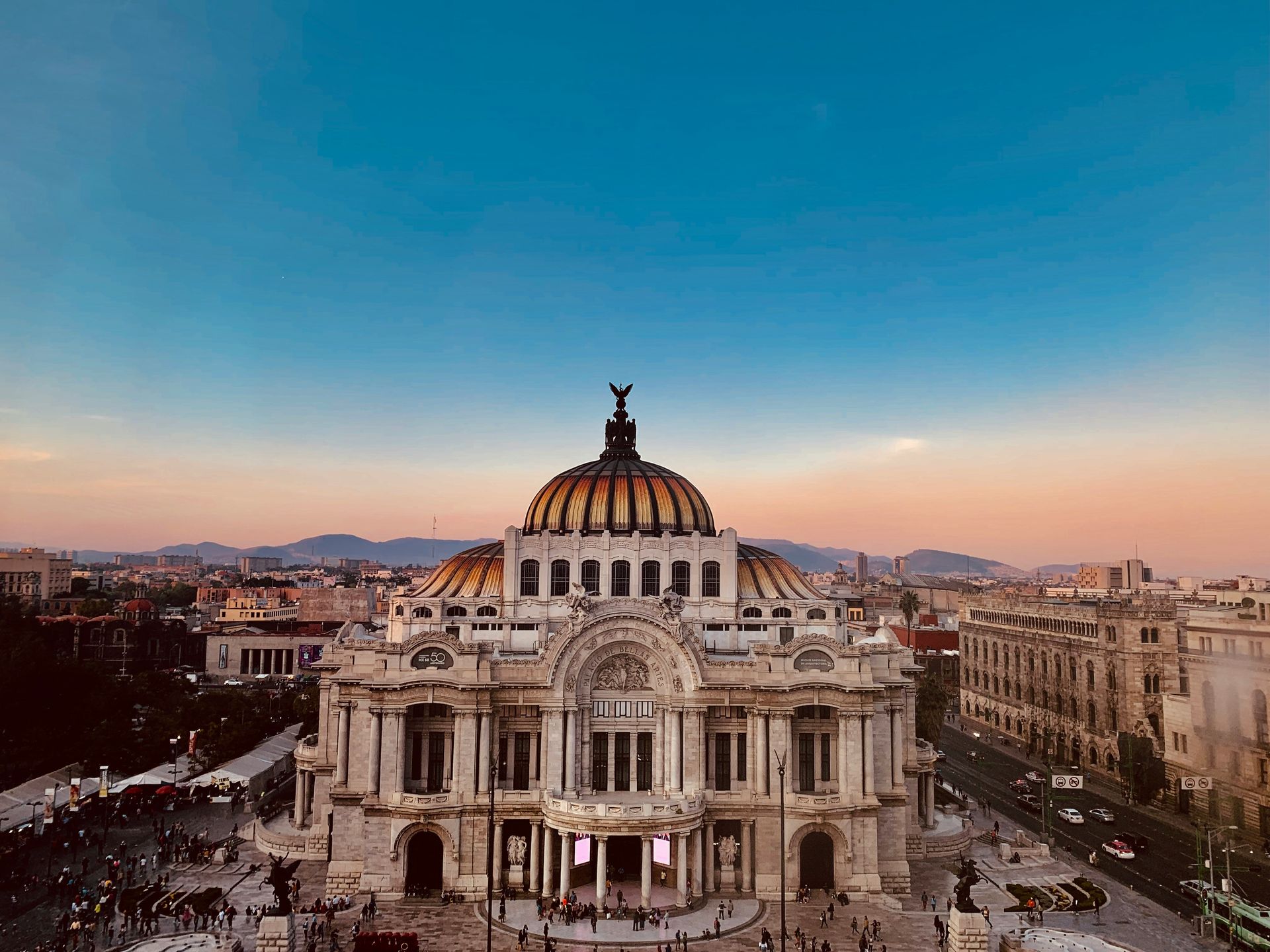 Palacio de Bellas Artes, Mexico City, with its ornate white facade, gold dome, under a twilight sky.