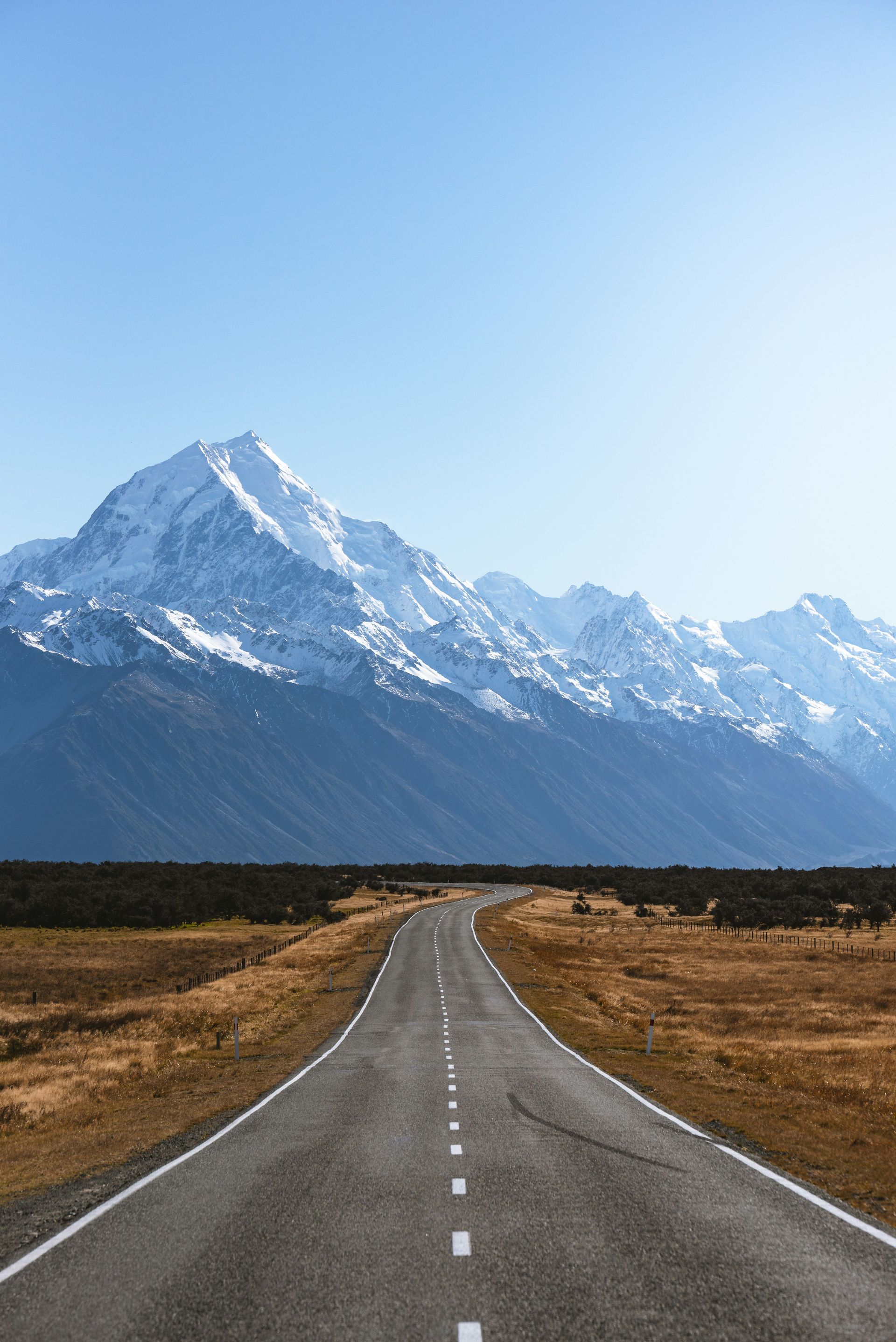 A road going through a field with Mount Cook in the background in New Zealand.