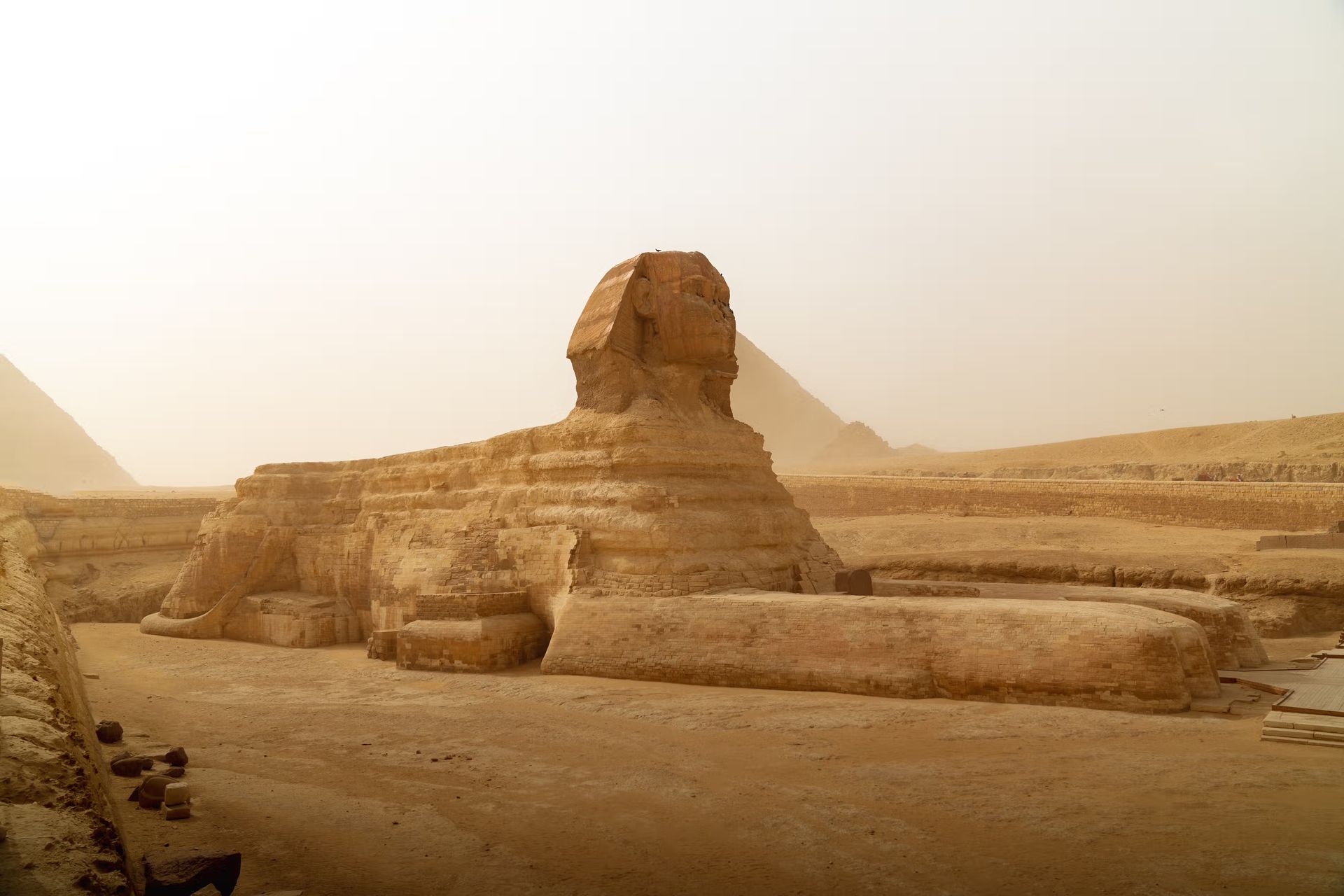 The sphinx is standing in the middle of the desert in front of the pyramids in Cairo, Egypt.