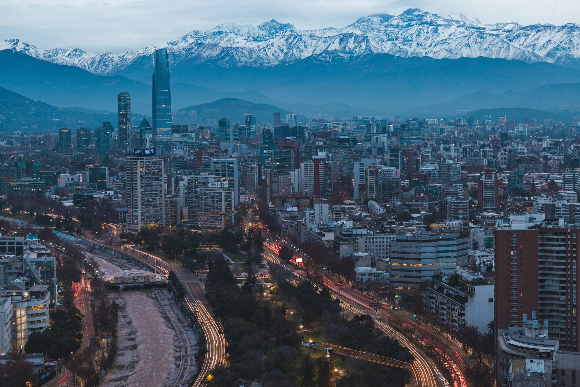 Santiago, Chile city skyline with snowy Andes mountains in the background at dusk.